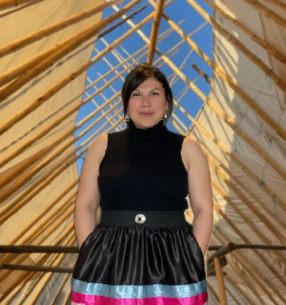Woman wearing a black sleeveless top and skirt standing inside a wooden framework structure.