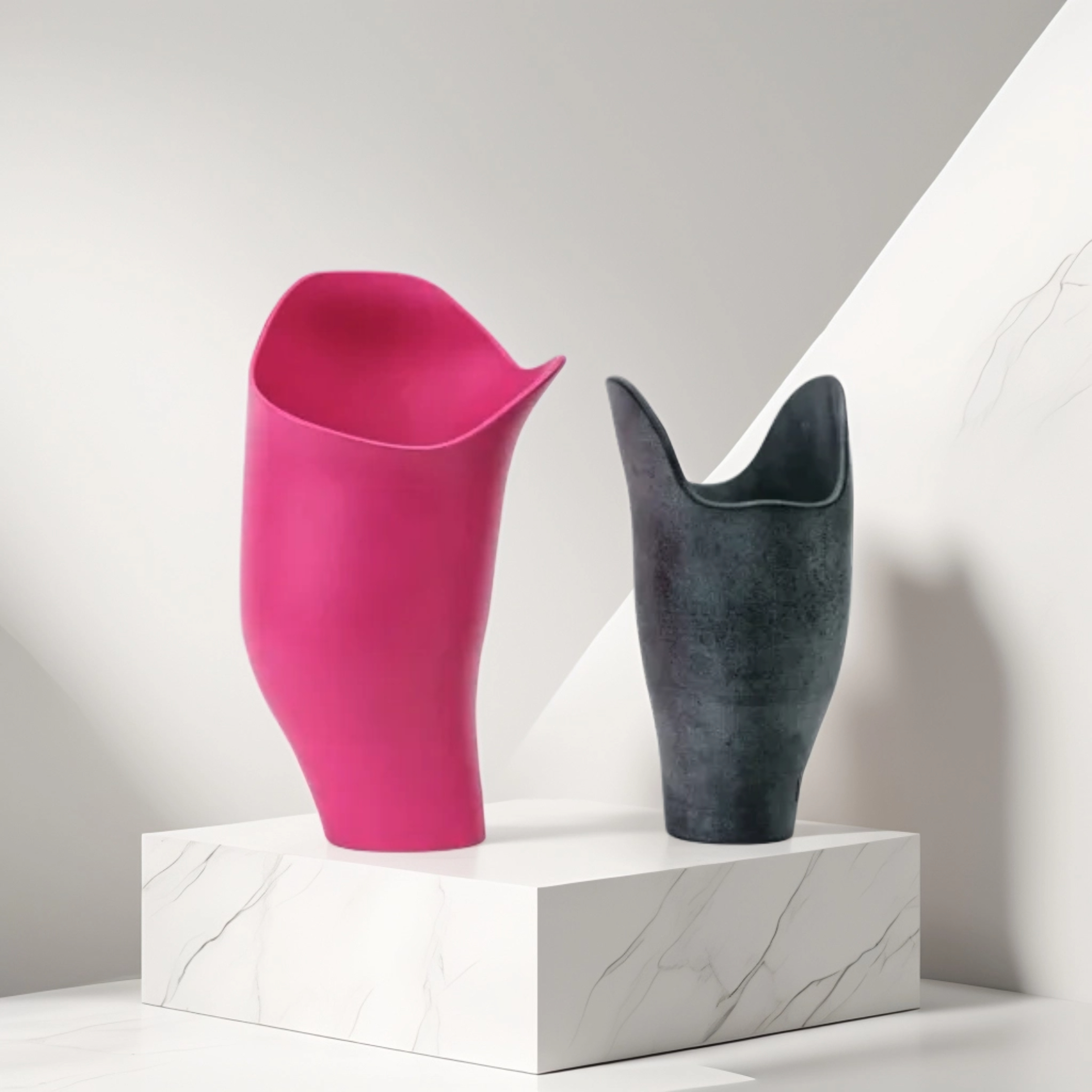 Two modern prosthetic below-knee sockets on a white marble pedestal, one pink and one black.