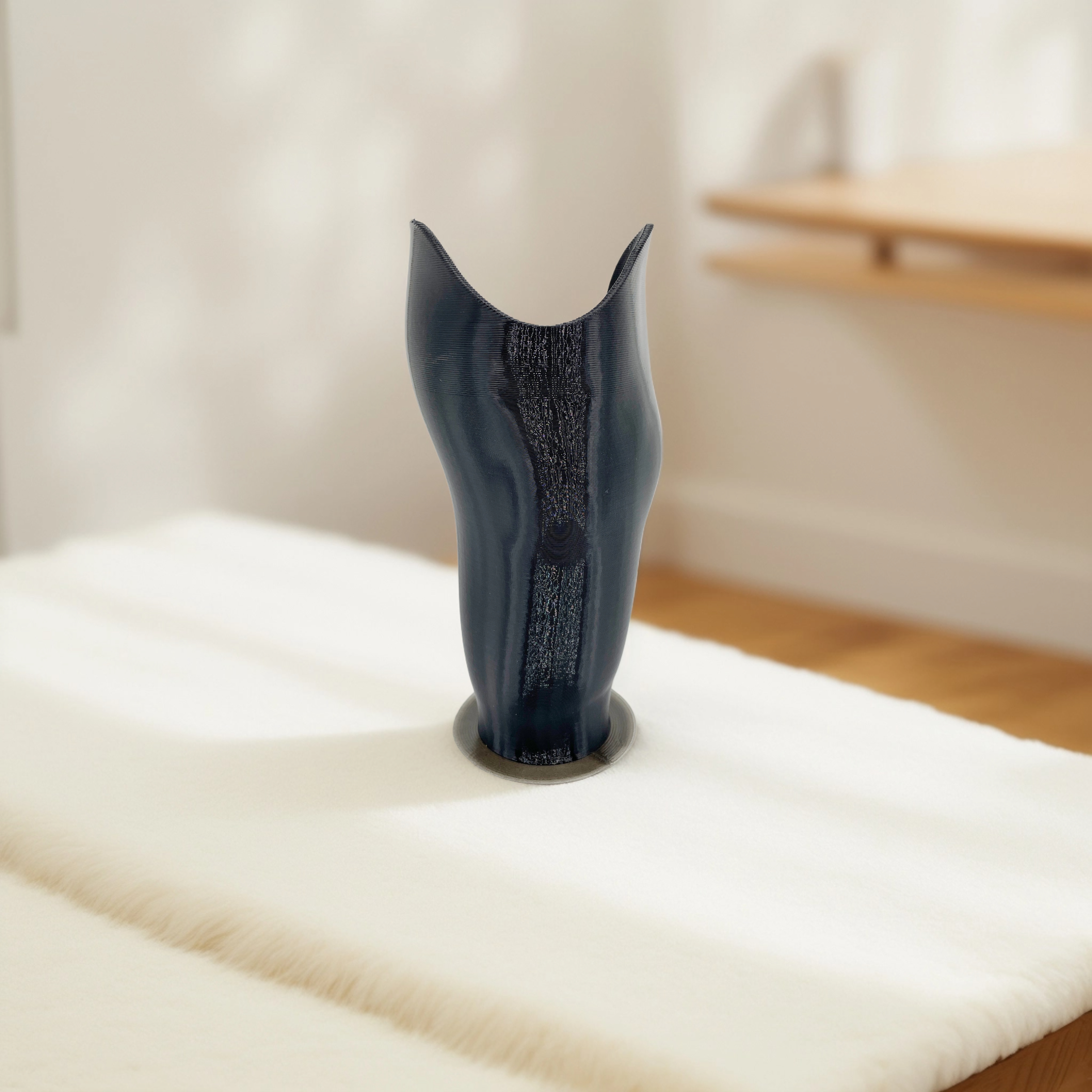 Dark blue prosthetic leg socket with textured center standing upright on a white surface.
