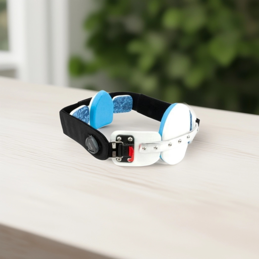 Adjustable black and white brace with blue padded supports on a light wooden surface.