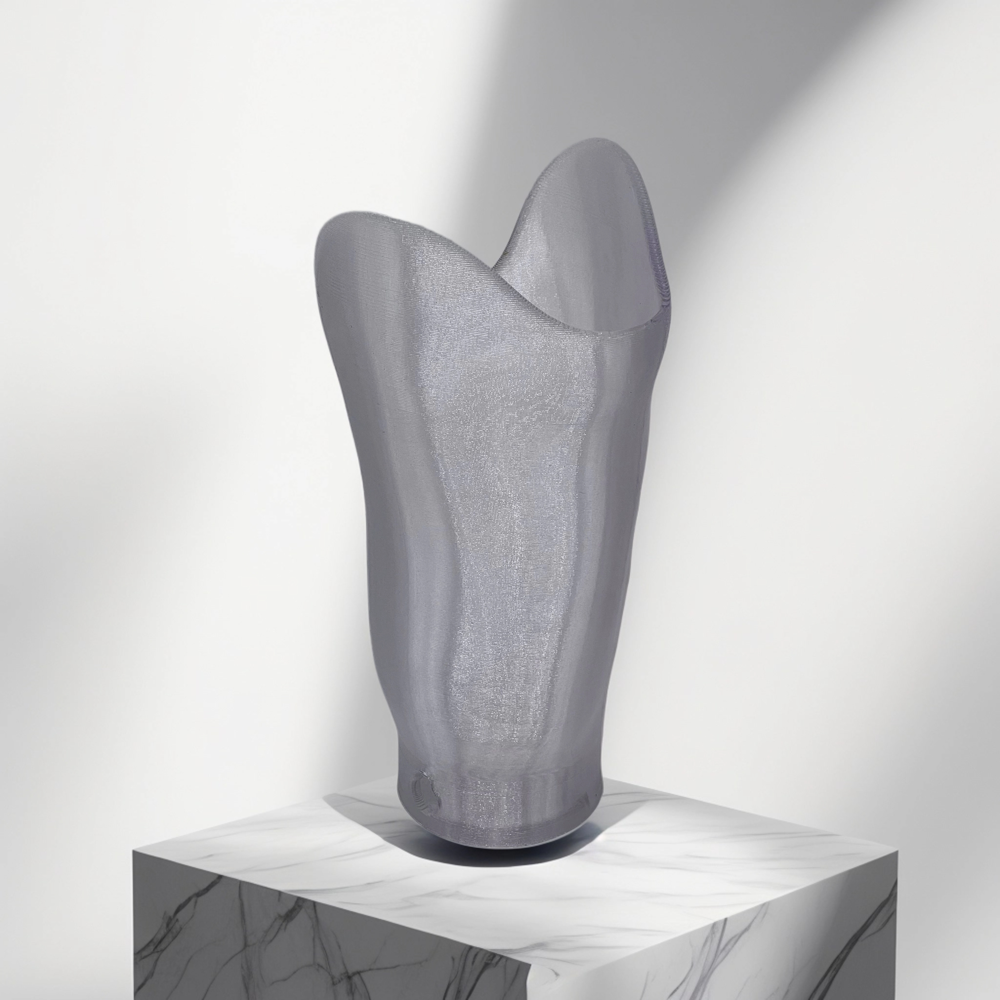 Translucent gray prosthetic socket displayed on a white marble pedestal with soft lighting.
