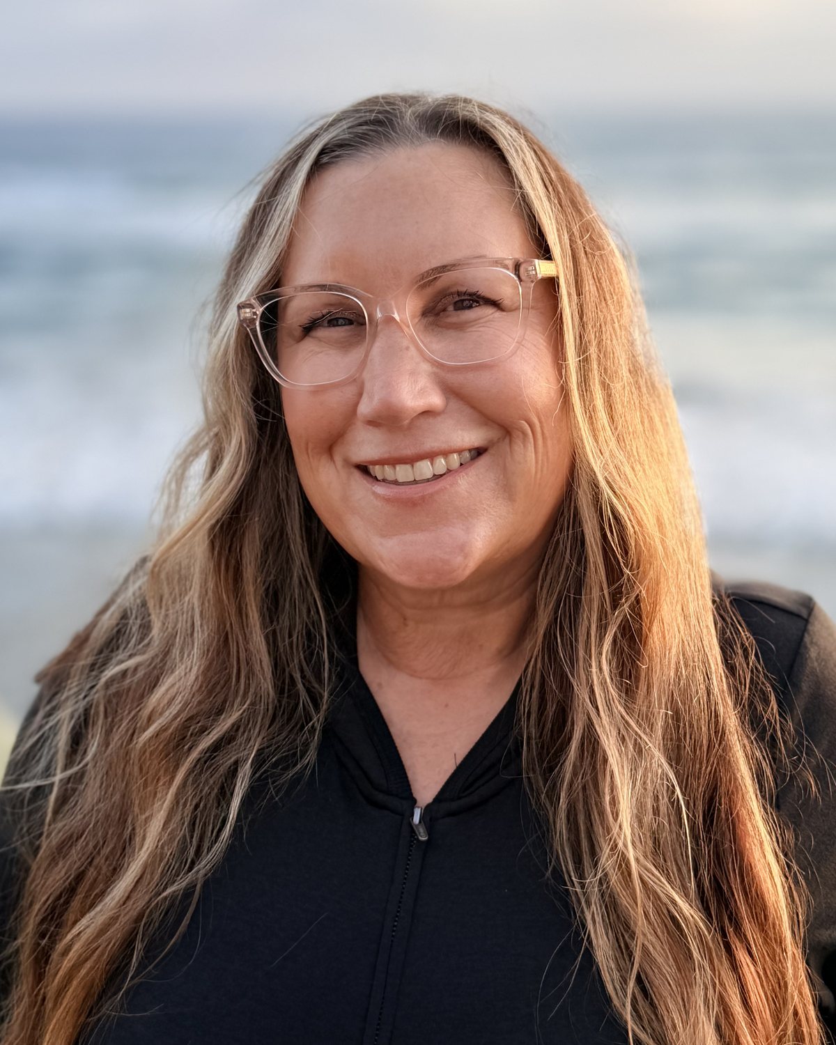 Rachel Edsall, co-founder of 10/28 Wealth Management, standing on the Oceanside coastline at sunset