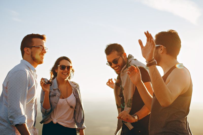 A diverse group of friends laughing together outdoors on a sunny day