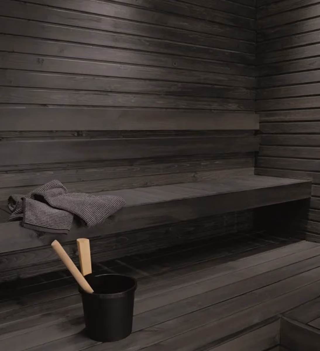 Black sauna interior with towel and wooden bucket
