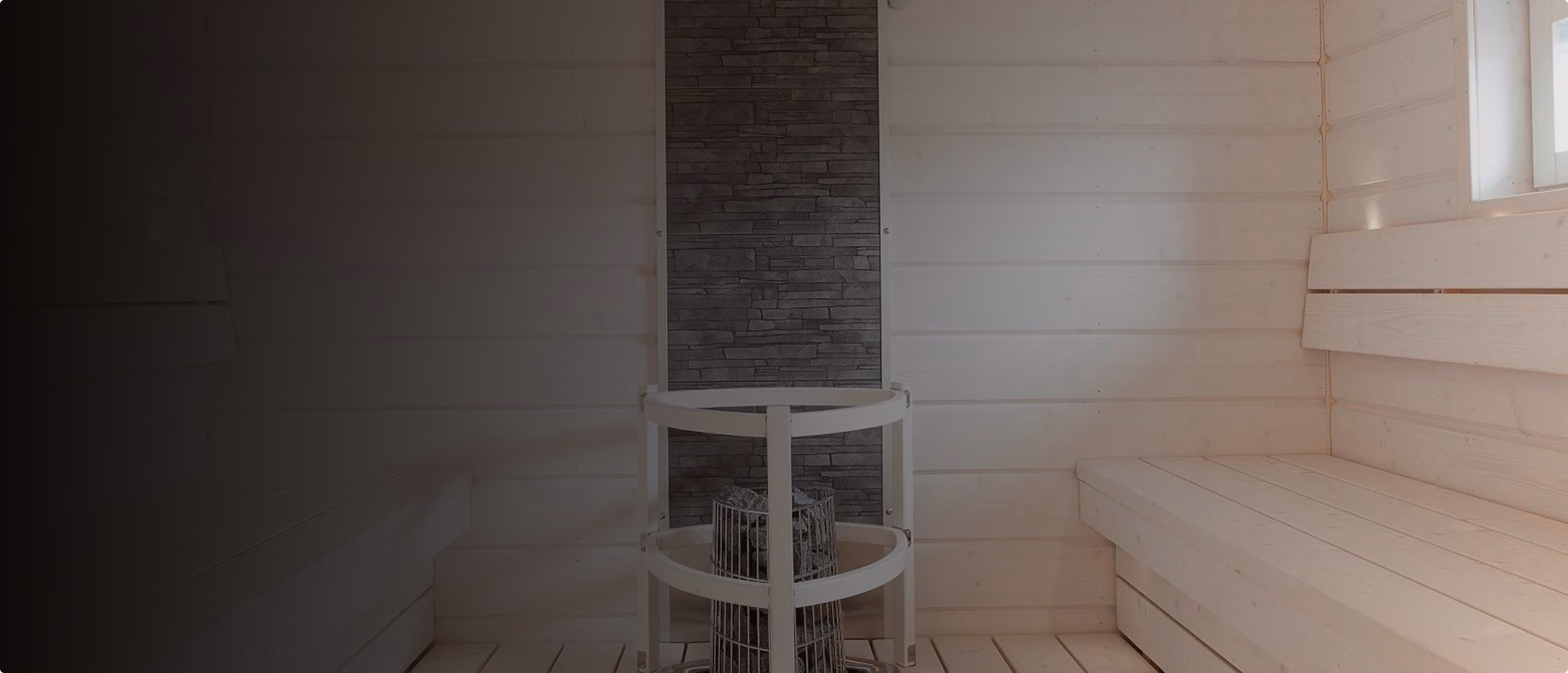White timber sauna with a round sauna heater and stone feature wall