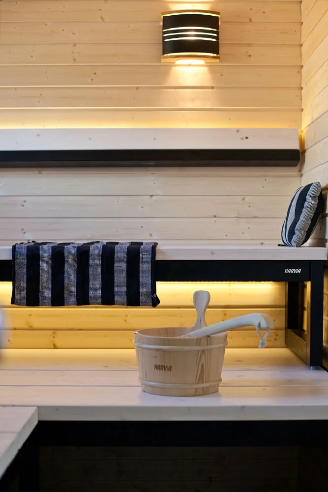 Sauna bench with backlighting, wall lamp and wooden sauna bucket