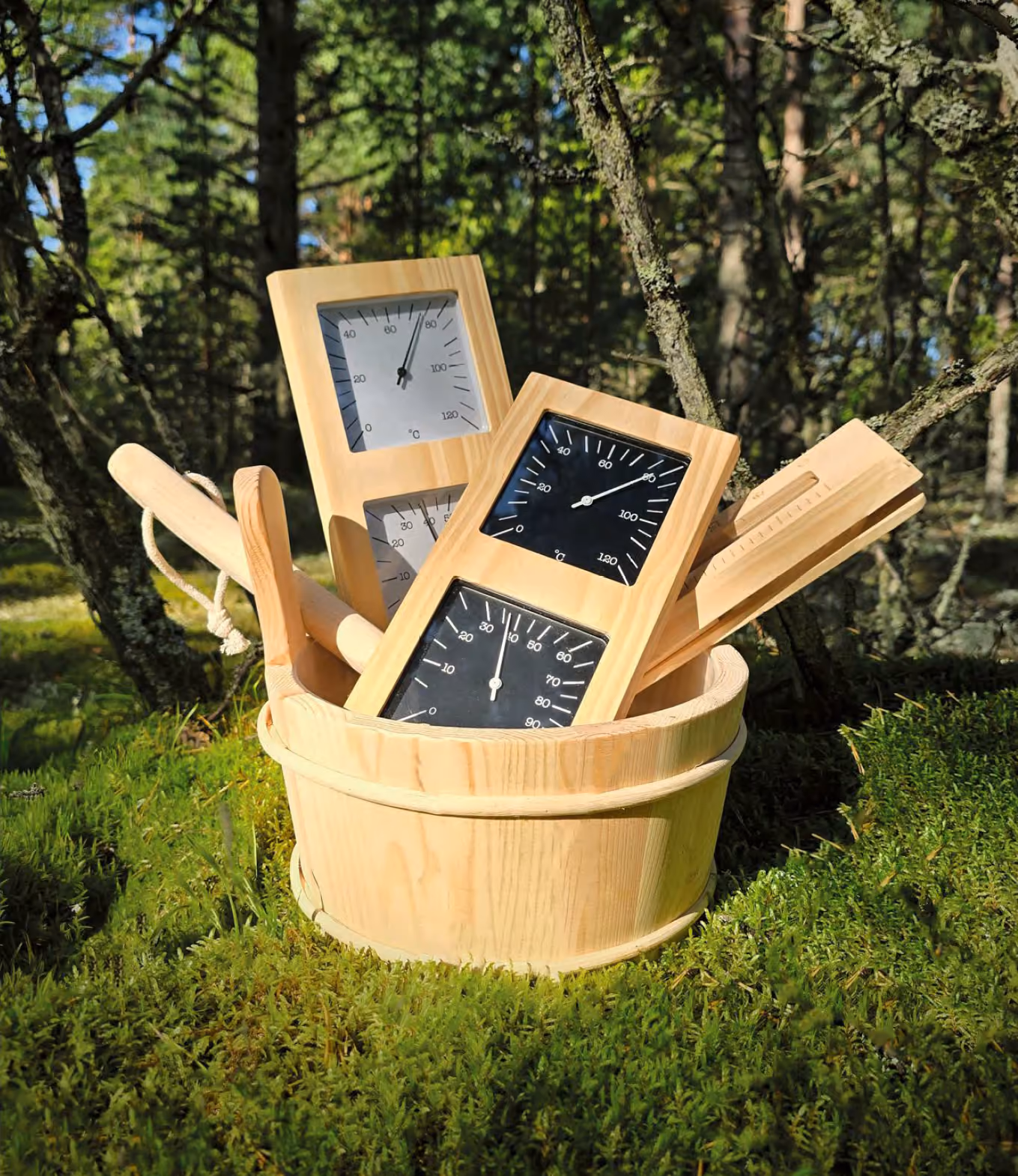 Wooden sauna bucket with thermometer and hygrometer accessories on moss
