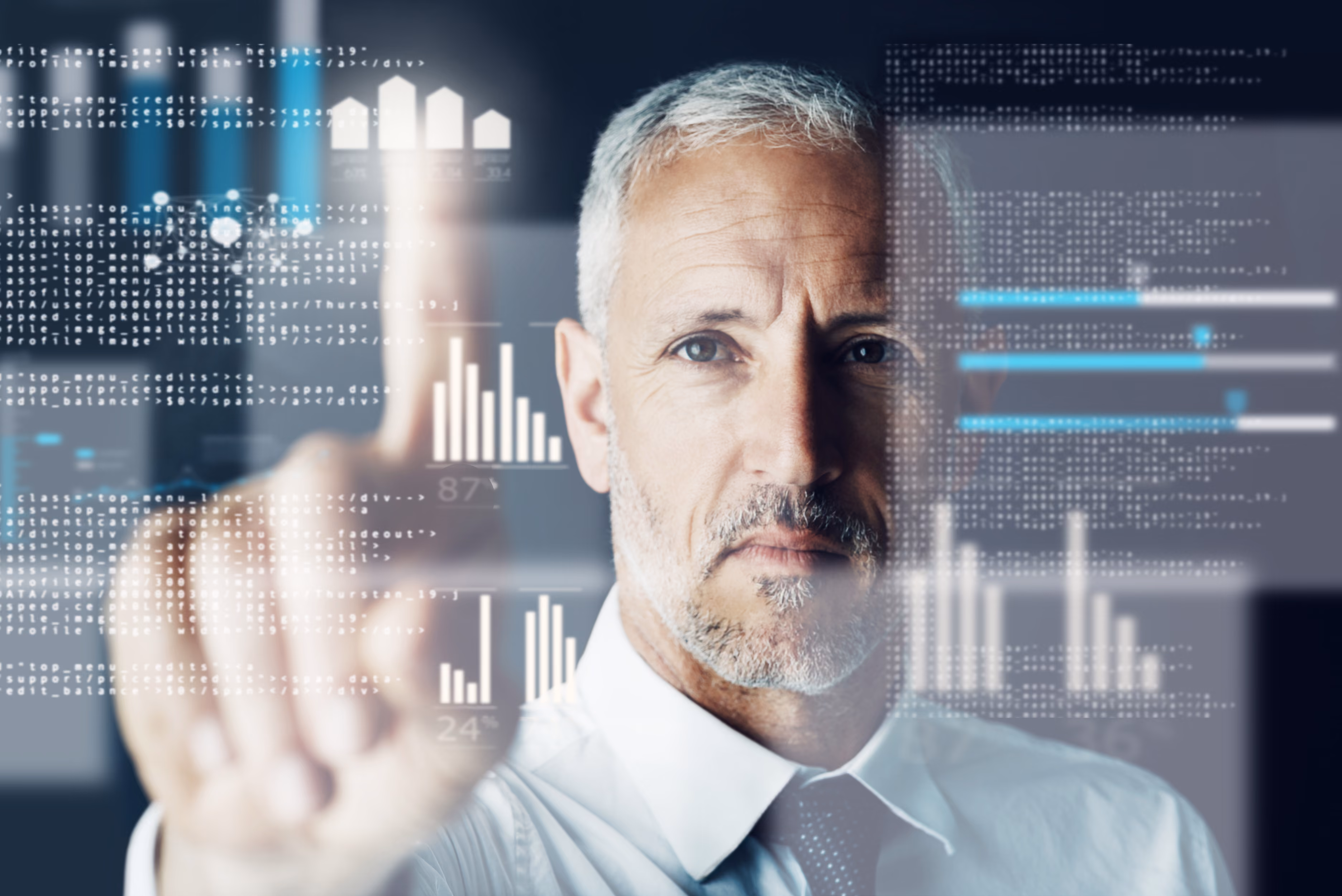 Focused businessman with gray hair and beard interacting with virtual financial data and graphs on a transparent screen.