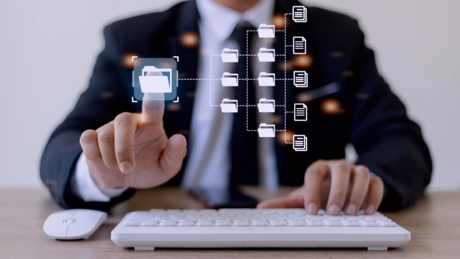 A person in a suit using a white keyboard and mouse at a desk, touching a floating digital folder icon connected to other folder and document icons in a network hierarchy.