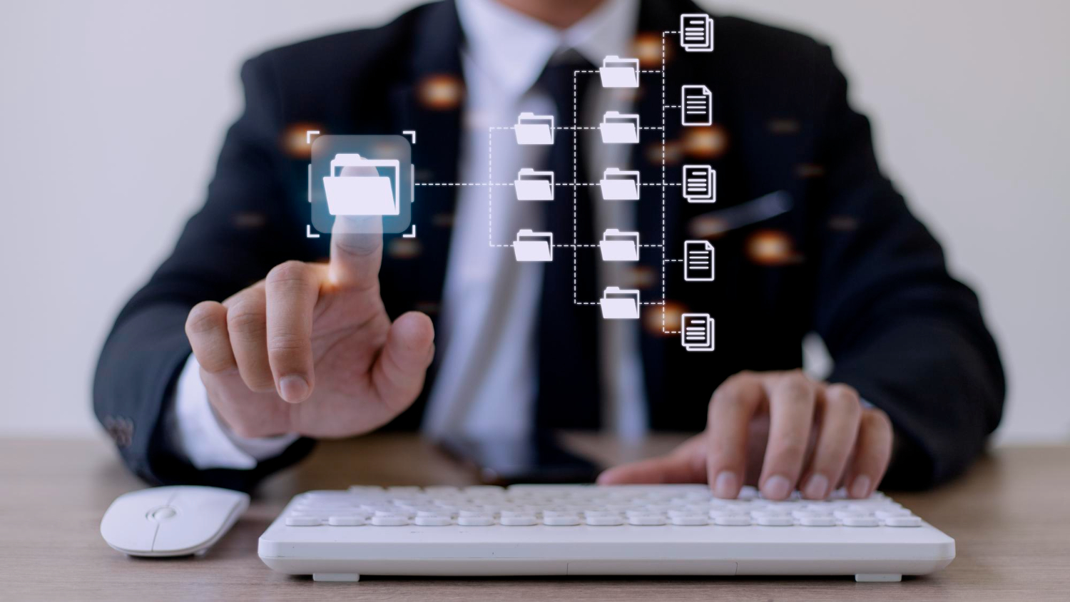 A person in a suit using a white keyboard and mouse at a desk, touching a floating digital folder icon connected to other folder and document icons in a network hierarchy.