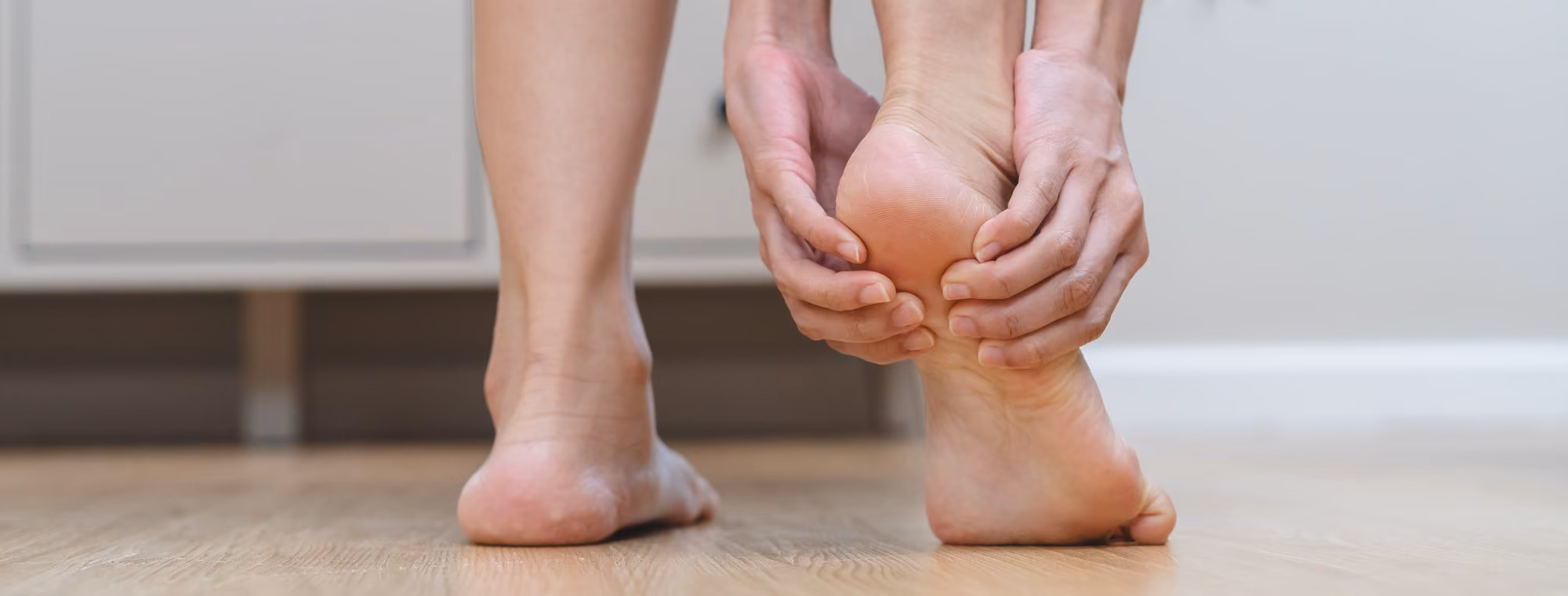 Person holding their heel in pain from plantar fasciitis