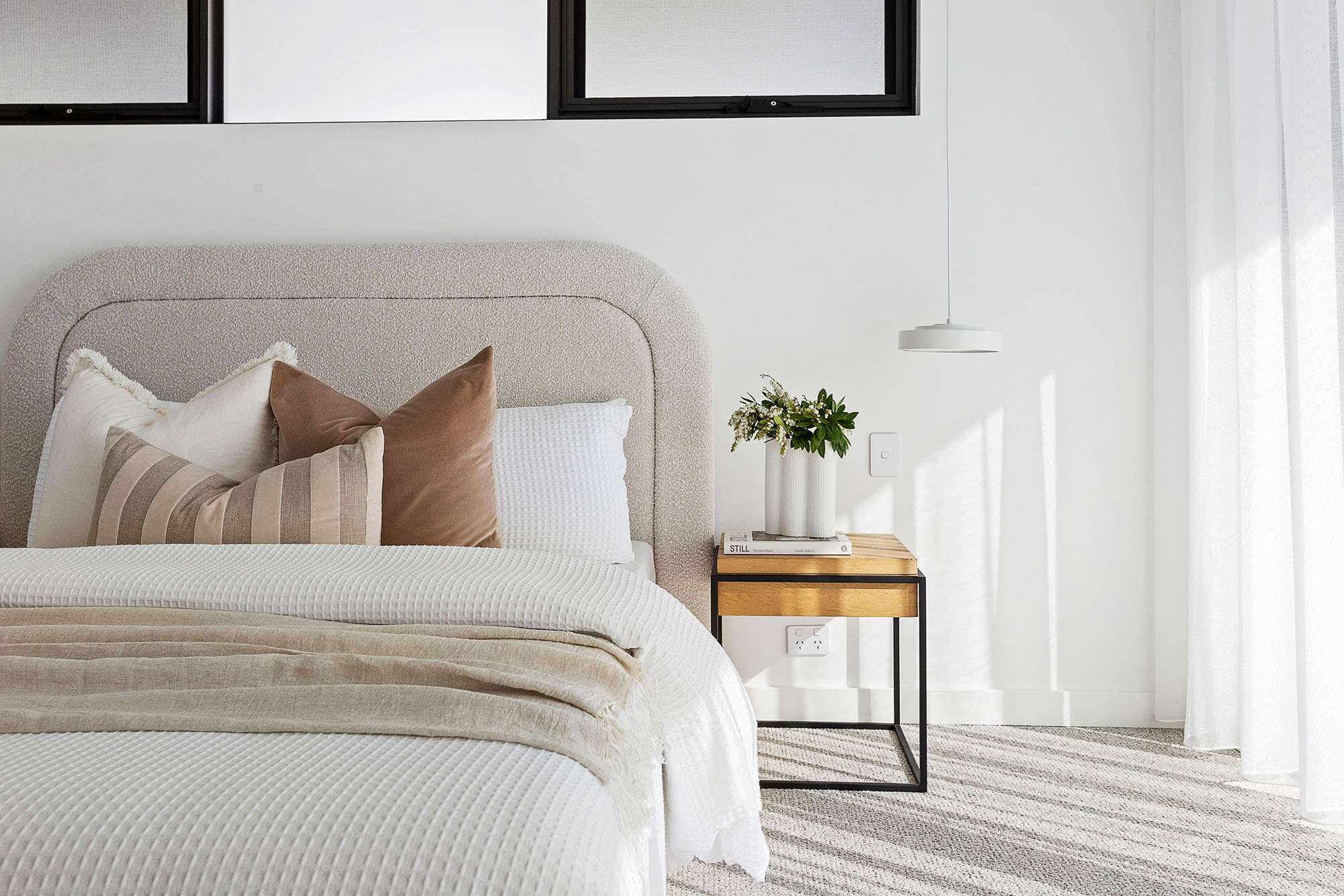 Styled bedroom with upholstered headboard and bedside table