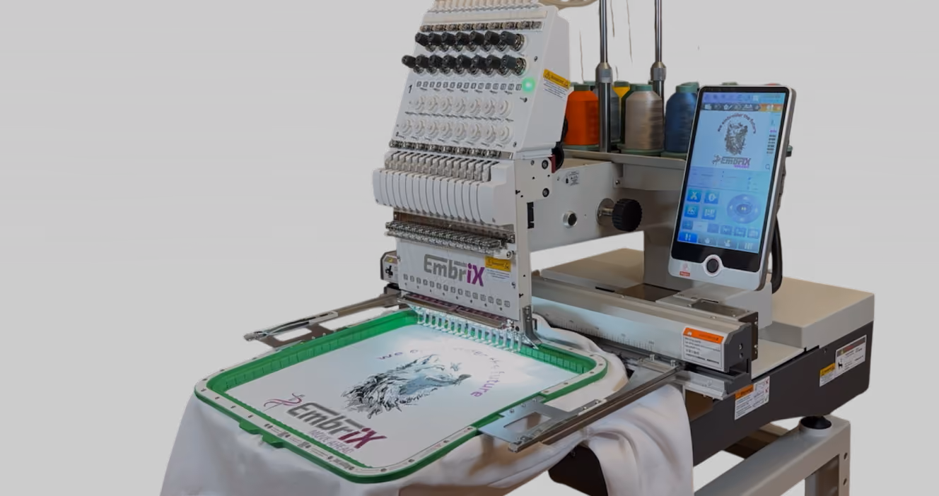 Industrielle Stickmaschine bestickt ein weißes T-Shirt mit einem Wolfsdesign und Text.