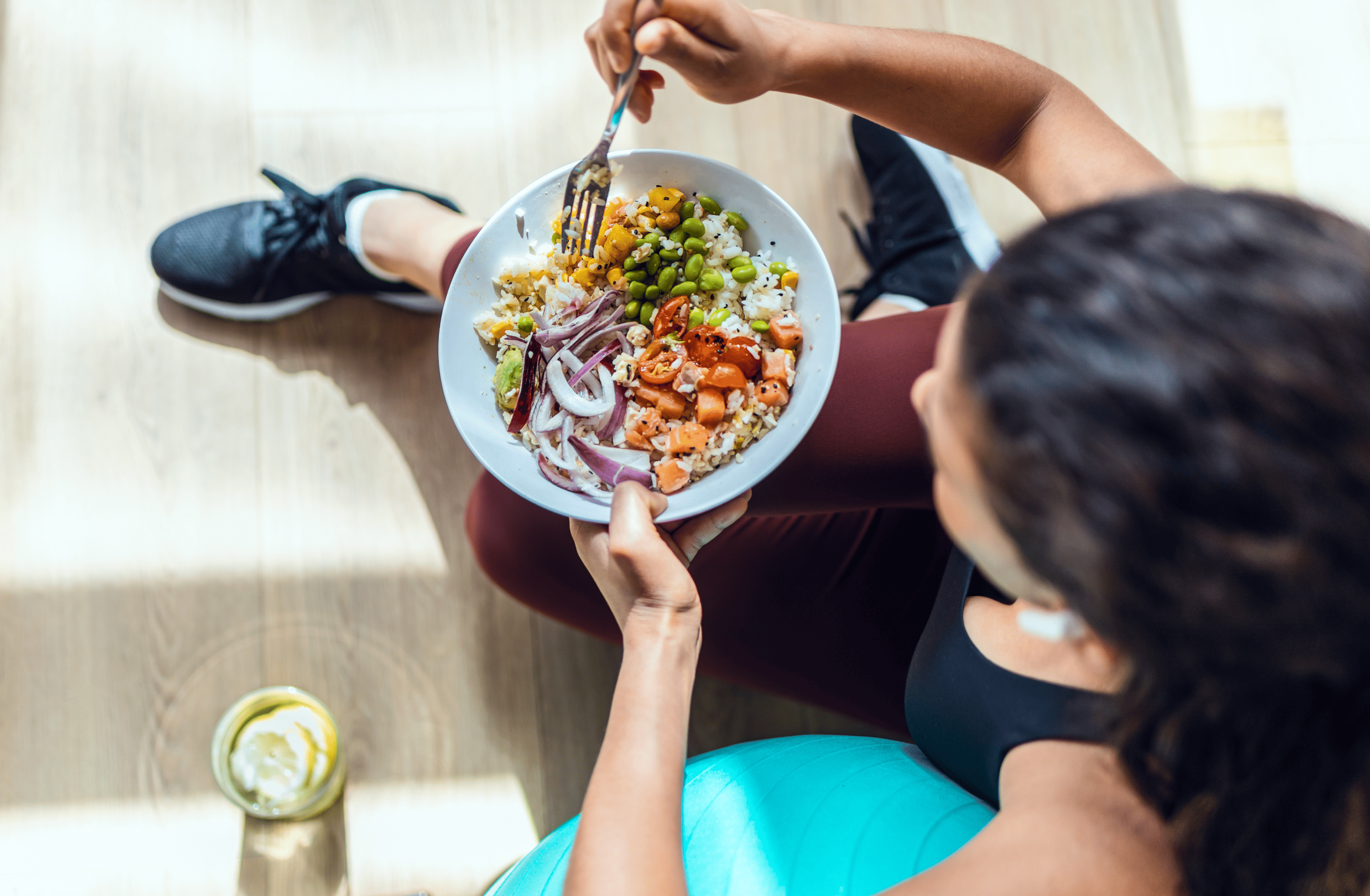 a woman sitting on the floor eating a bowl of food