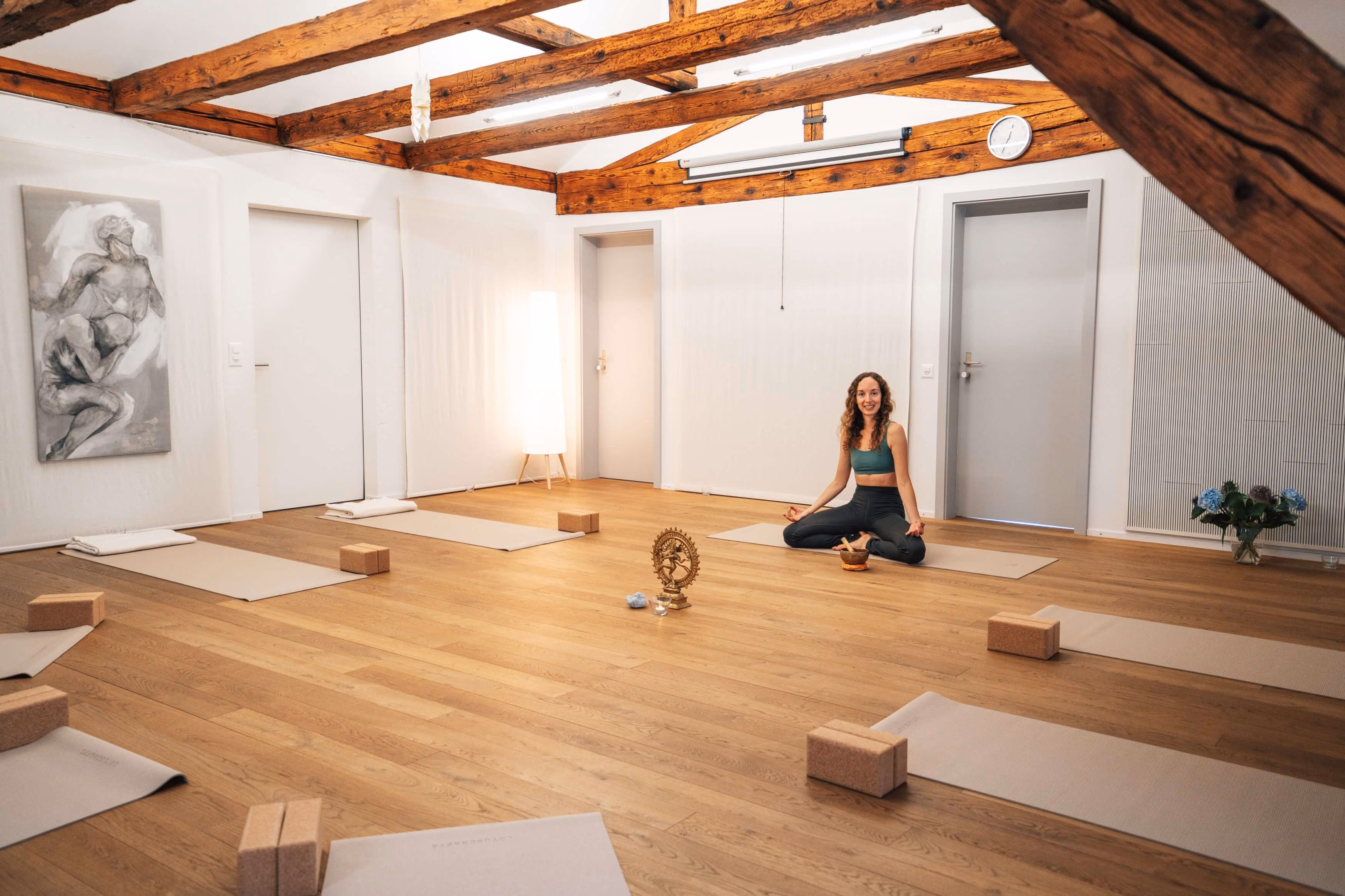 Yvonne Buttet meditiert in einem hellen Yogaraum in Luzern, umgeben von Yogamatten in der Akademie für Bildung und Transformation.