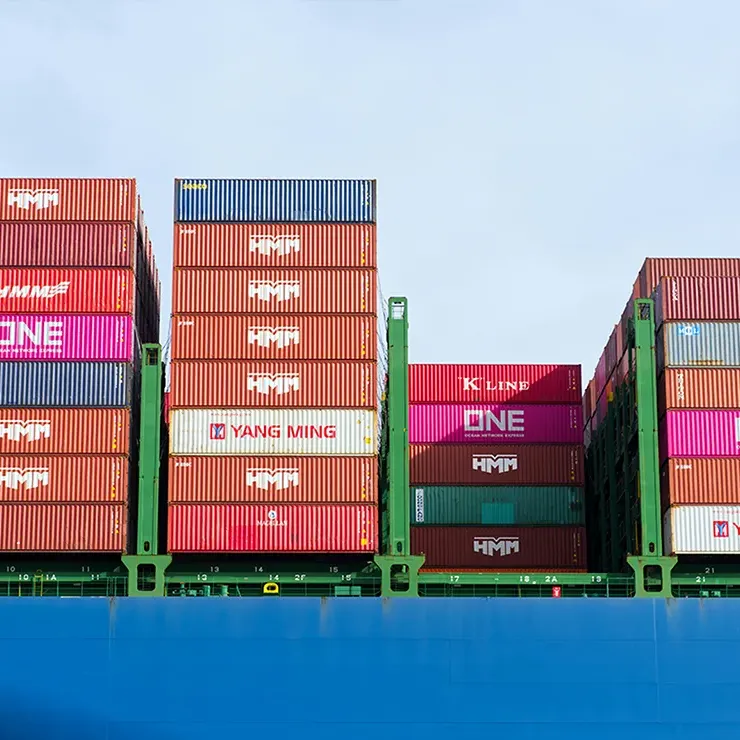 Stacks of colourful cargo containers on a large blue freight ship.