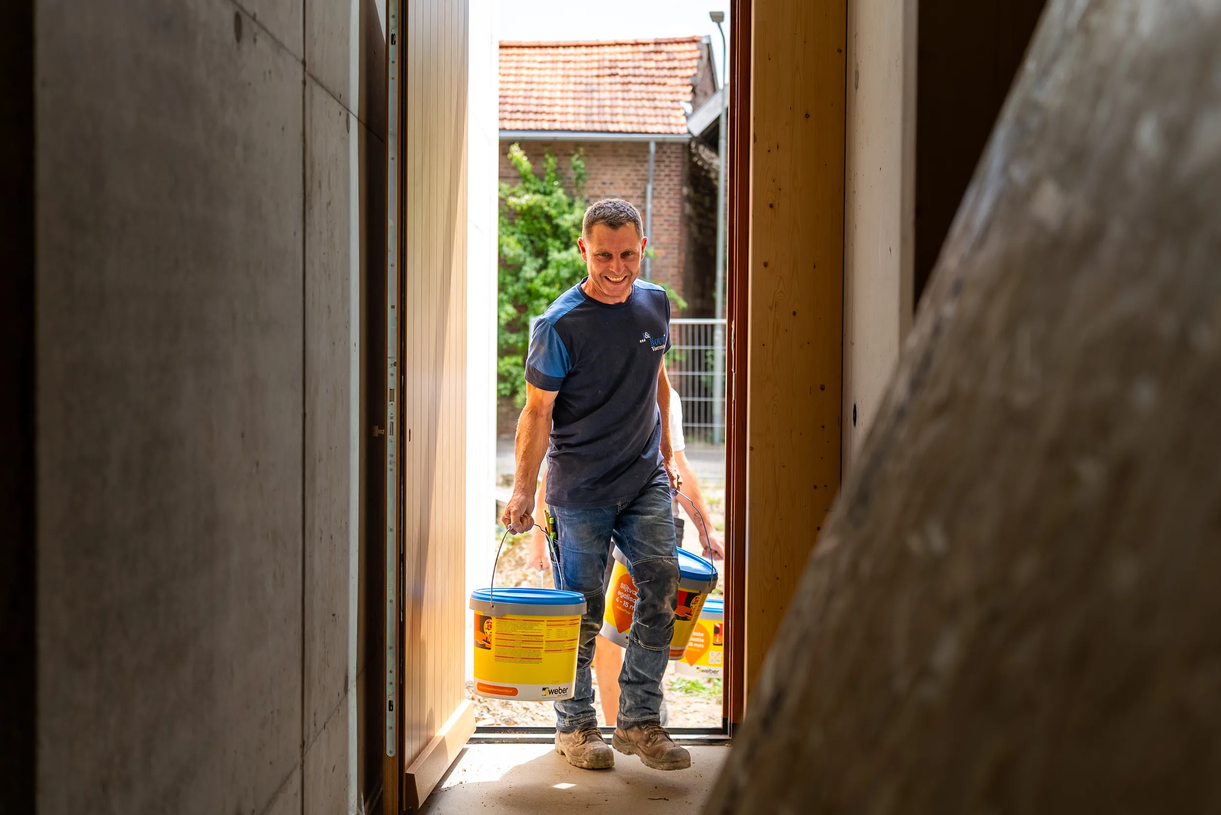 Medewerker draagt materiaal naar binnen op een nieuwbouwproject