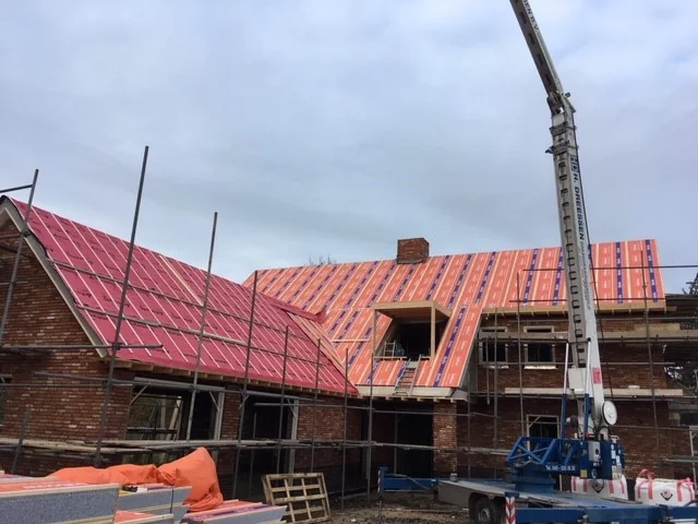 Geïsoleerde dakelementen worden met een autolaadkraan op het dak van de nieuwbouwwoning gelegd