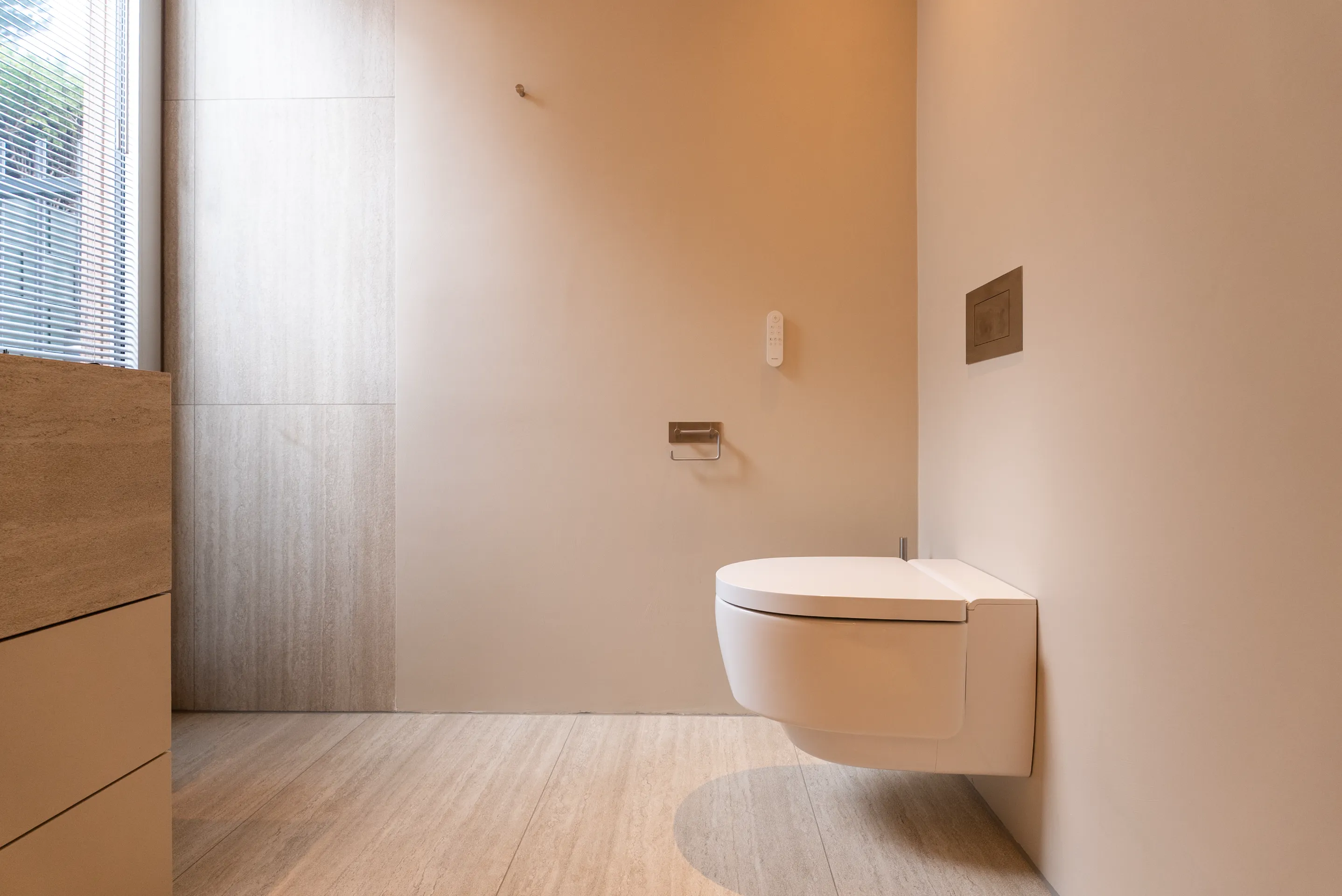 Badkamer met hangend toilet en doorlopende natuurstenen wand- en vloerafwerking