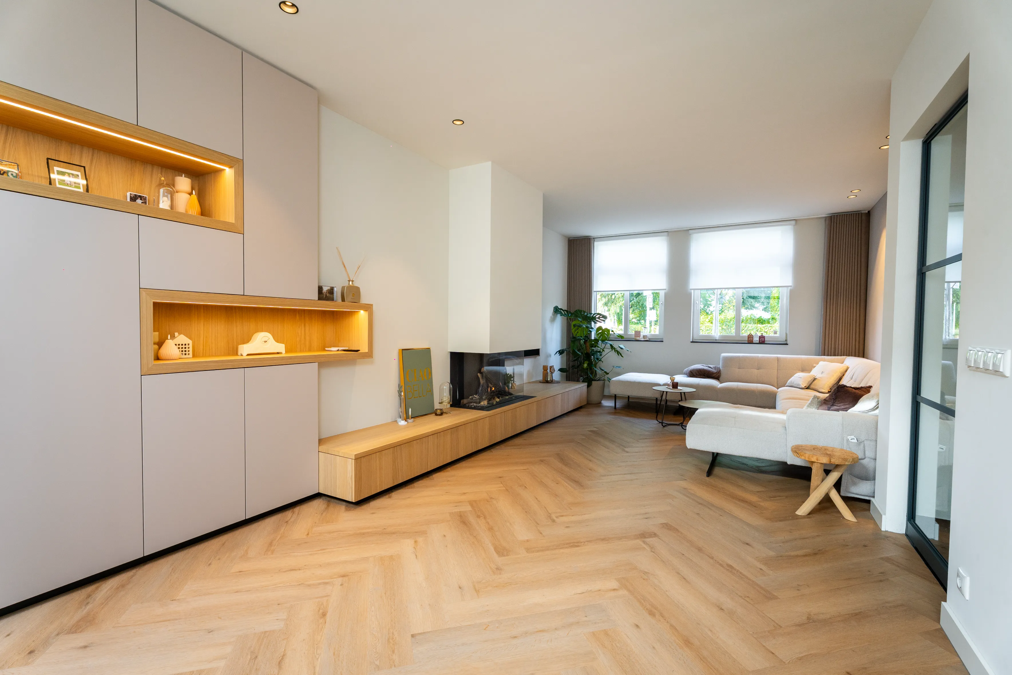 Woonkamer met visgraatvloer, ingebouwde kastenwand en zwevend eiken meubel