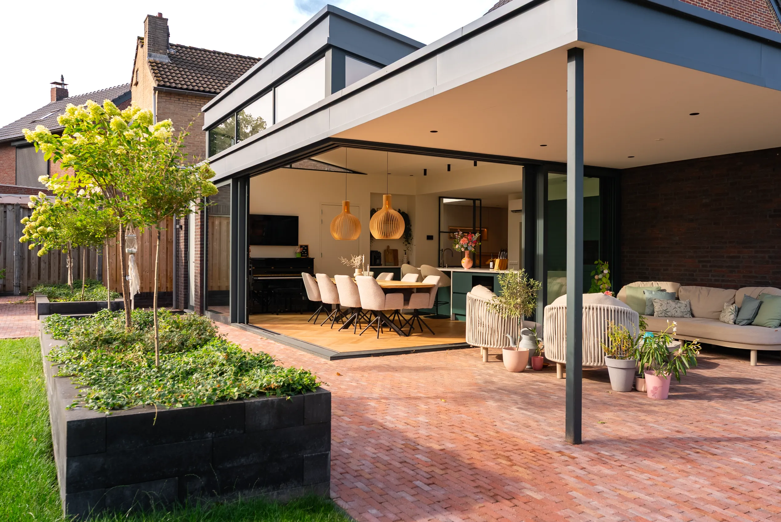 Aanbouw met plat dak en opbouw, gezien vanaf het terras onder de overkapping