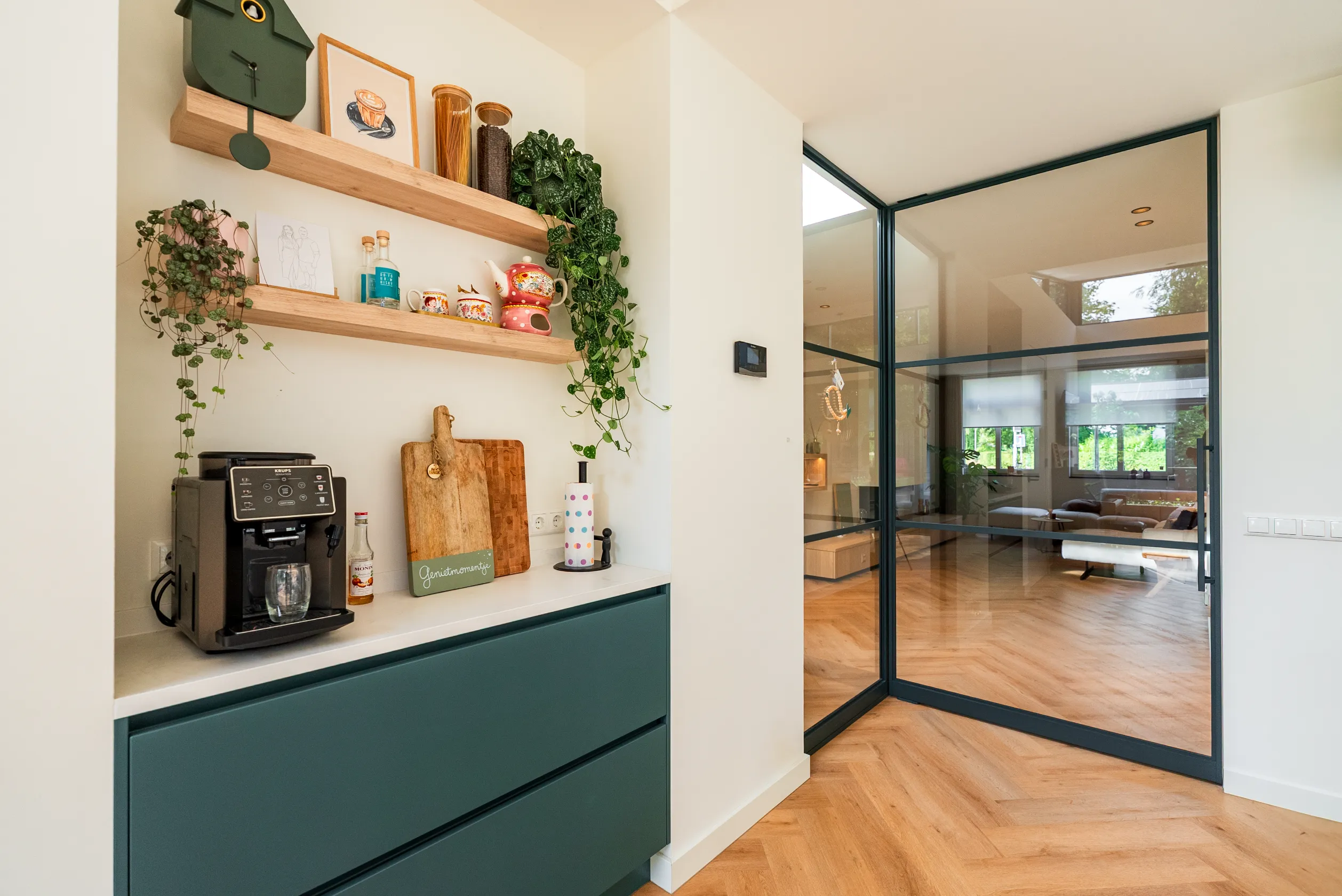 Koffiehoek met groene kastenwand naast de stalen taatsdeur naar de woonkamer