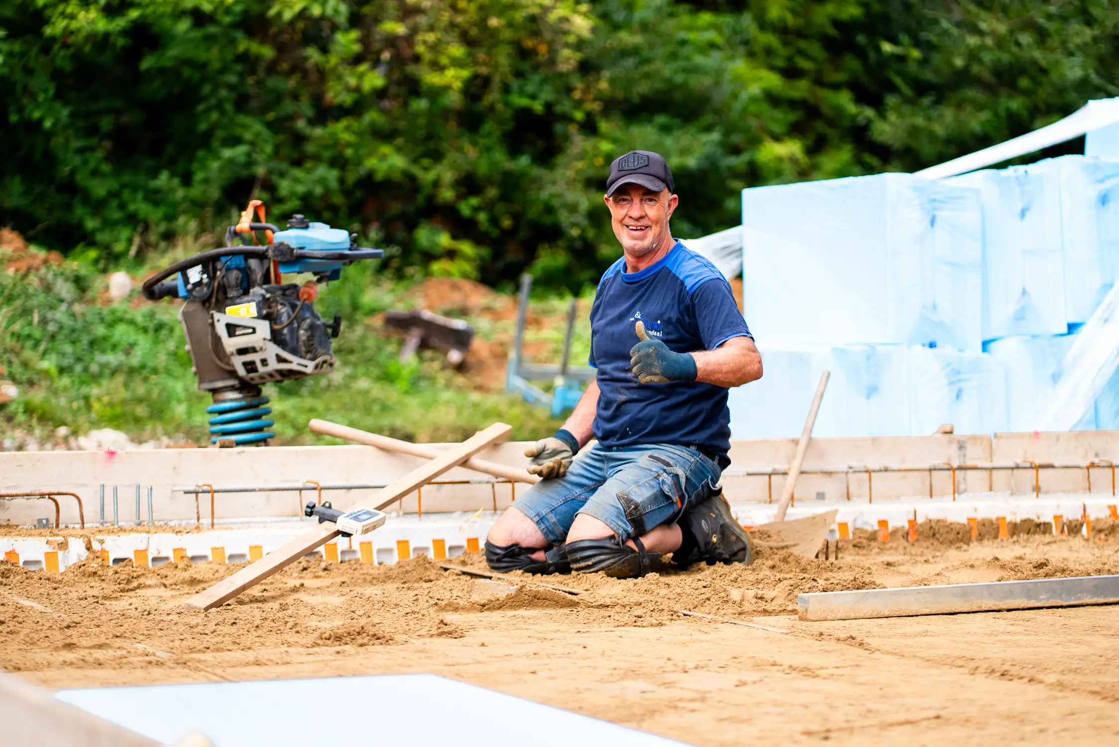 Timmerman van L&L Bouw bij de bekisting en de trilplaat op de bouwplaats