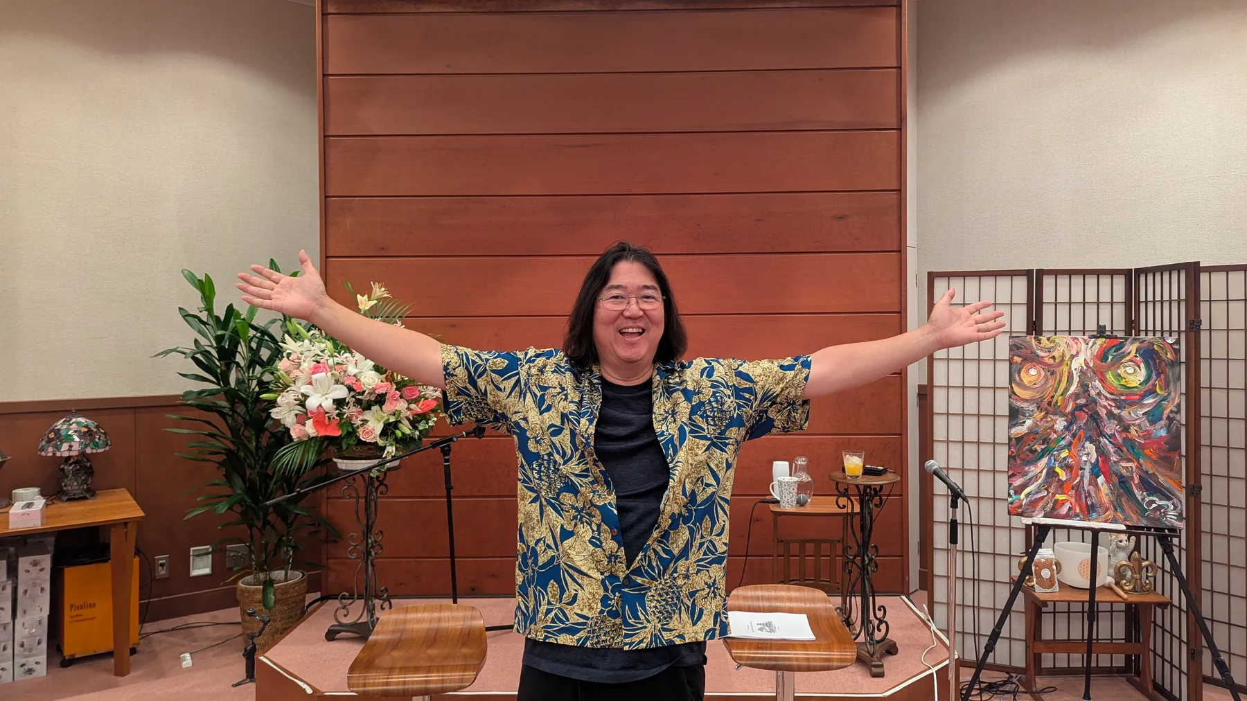 Ken Honda on stage with his arms thrown wide, welcoming the retreat circle