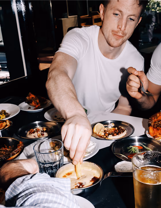 A guest dipping into hummus at a table of Le Bab dishes