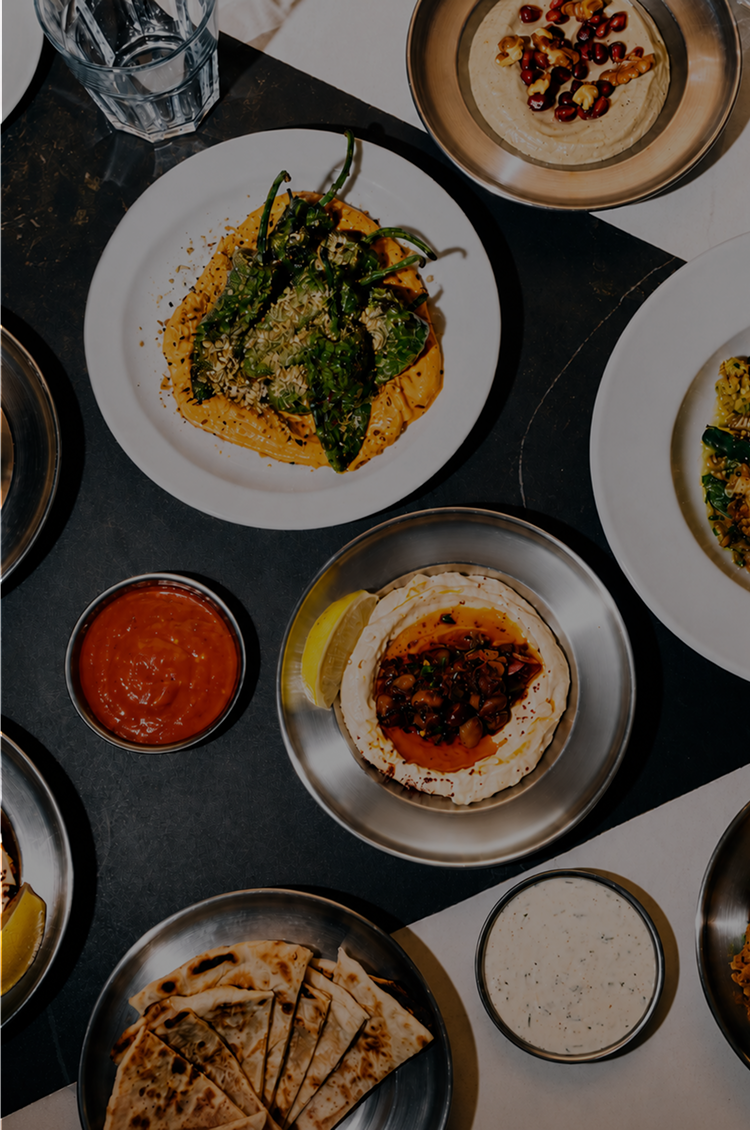 Various dishes including fried chicken, yellow rice, grilled fish, bread, and sauce on a marble table.