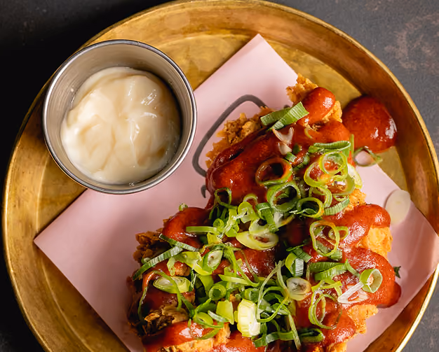 Open-faced sandwich with grilled chicken, cucumber slices, lettuce, seaweed, and orange sauce on white plate.