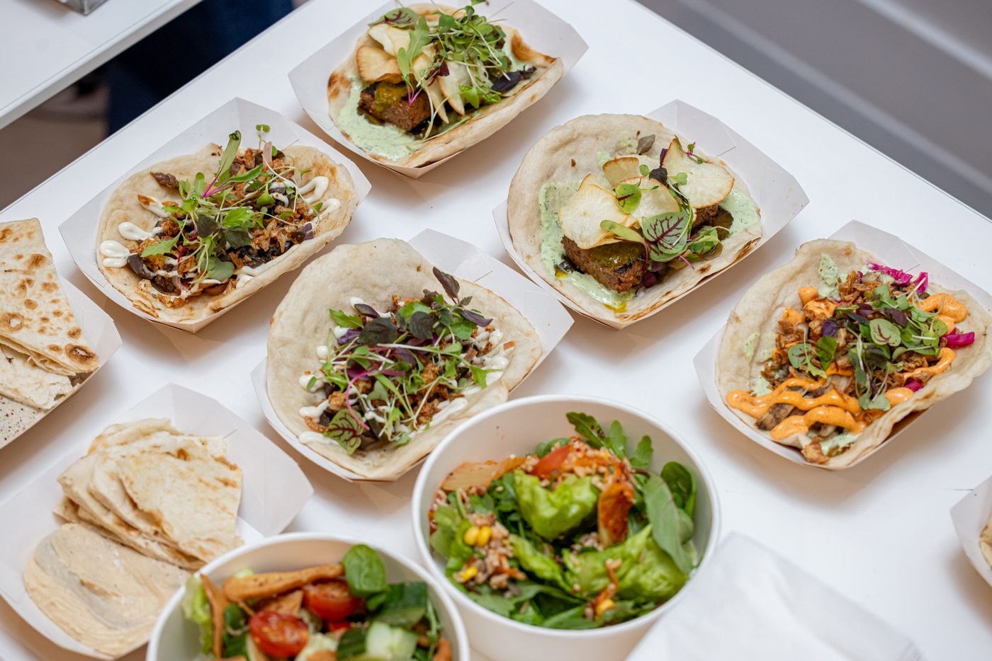 Open kebabs, flatbreads and salads laid out in catering trays