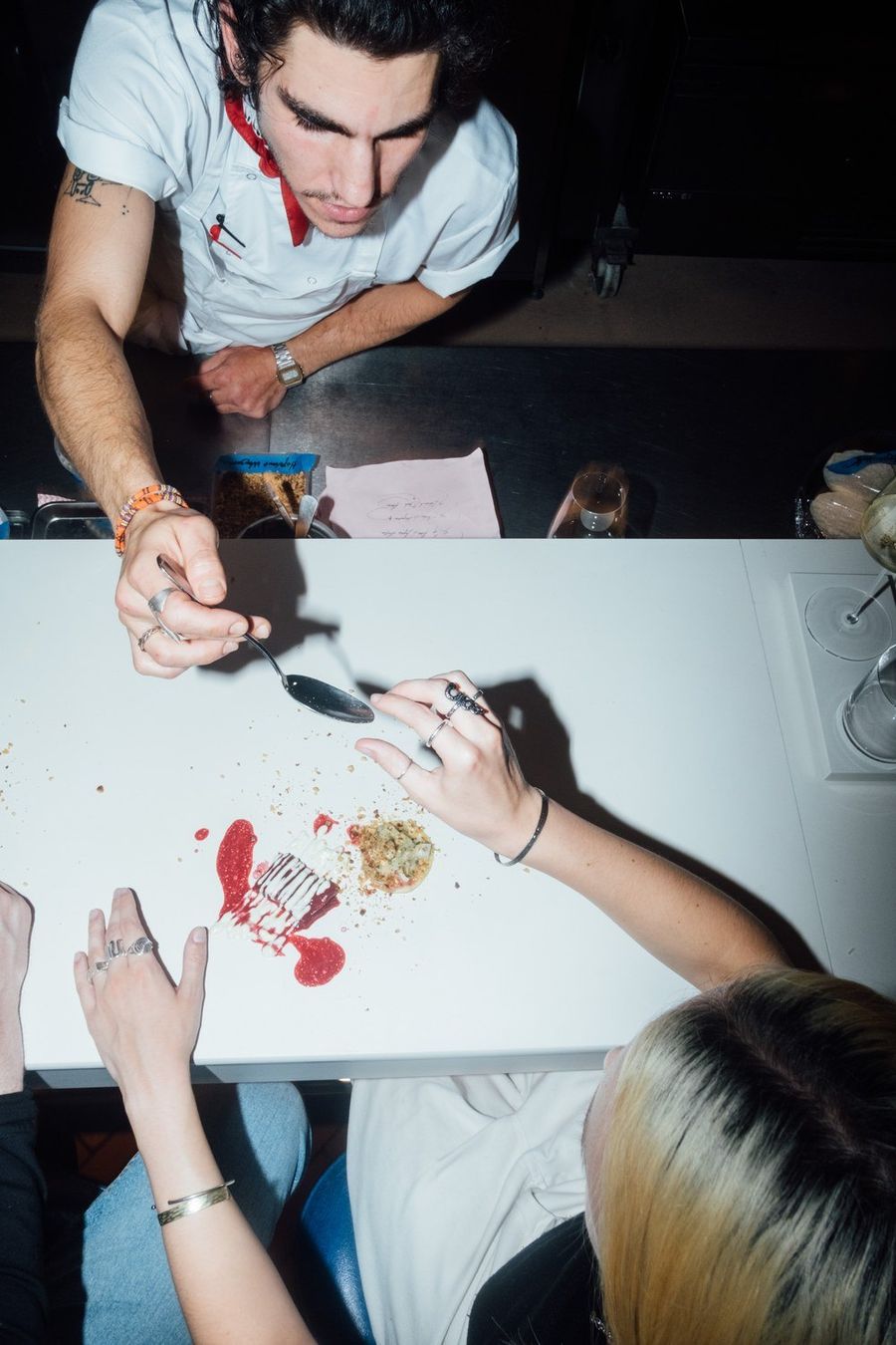 A chef plating a course straight onto the counter while a guest watches