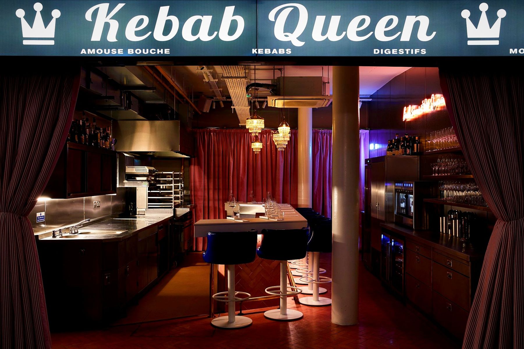 The Kebab Queen room under its neon sign, with velvet stools and red curtains