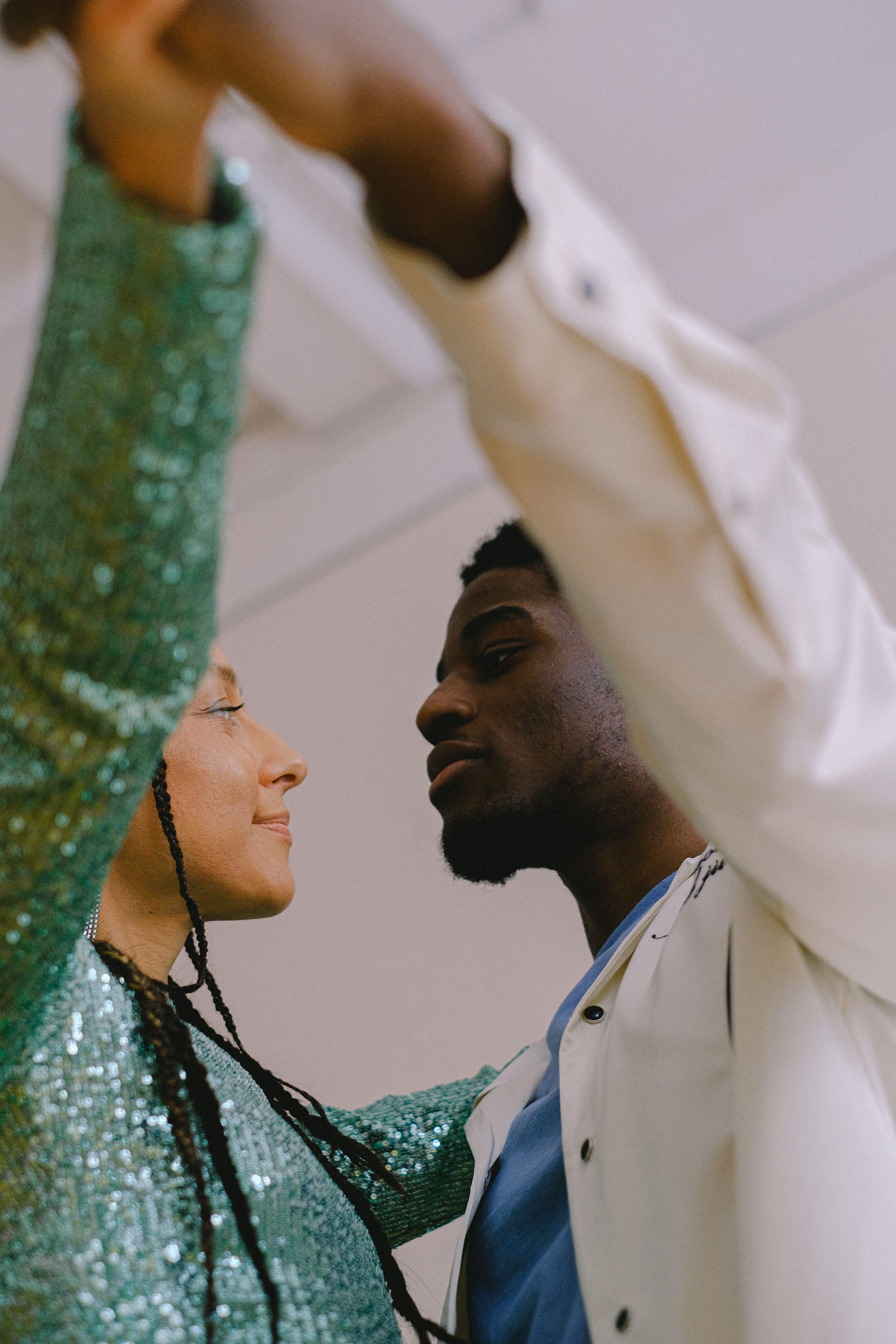 Close-up of a man and woman facing each other with raised arms, seemingly dancing.