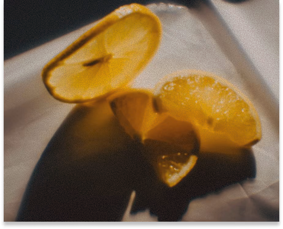 Two slices of bright yellow lemon resting on a surface with light shadows.