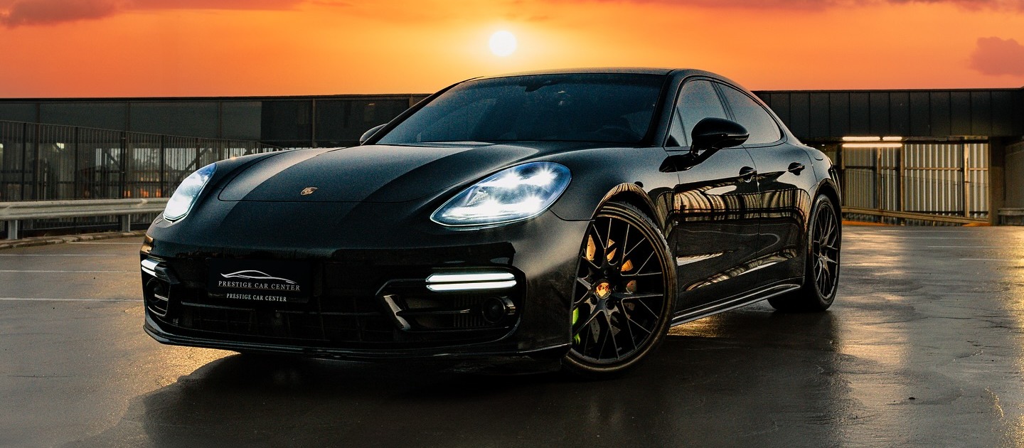 Juuri pesty musta Porsche Panamera märällä pinnalla auringonlaskussa