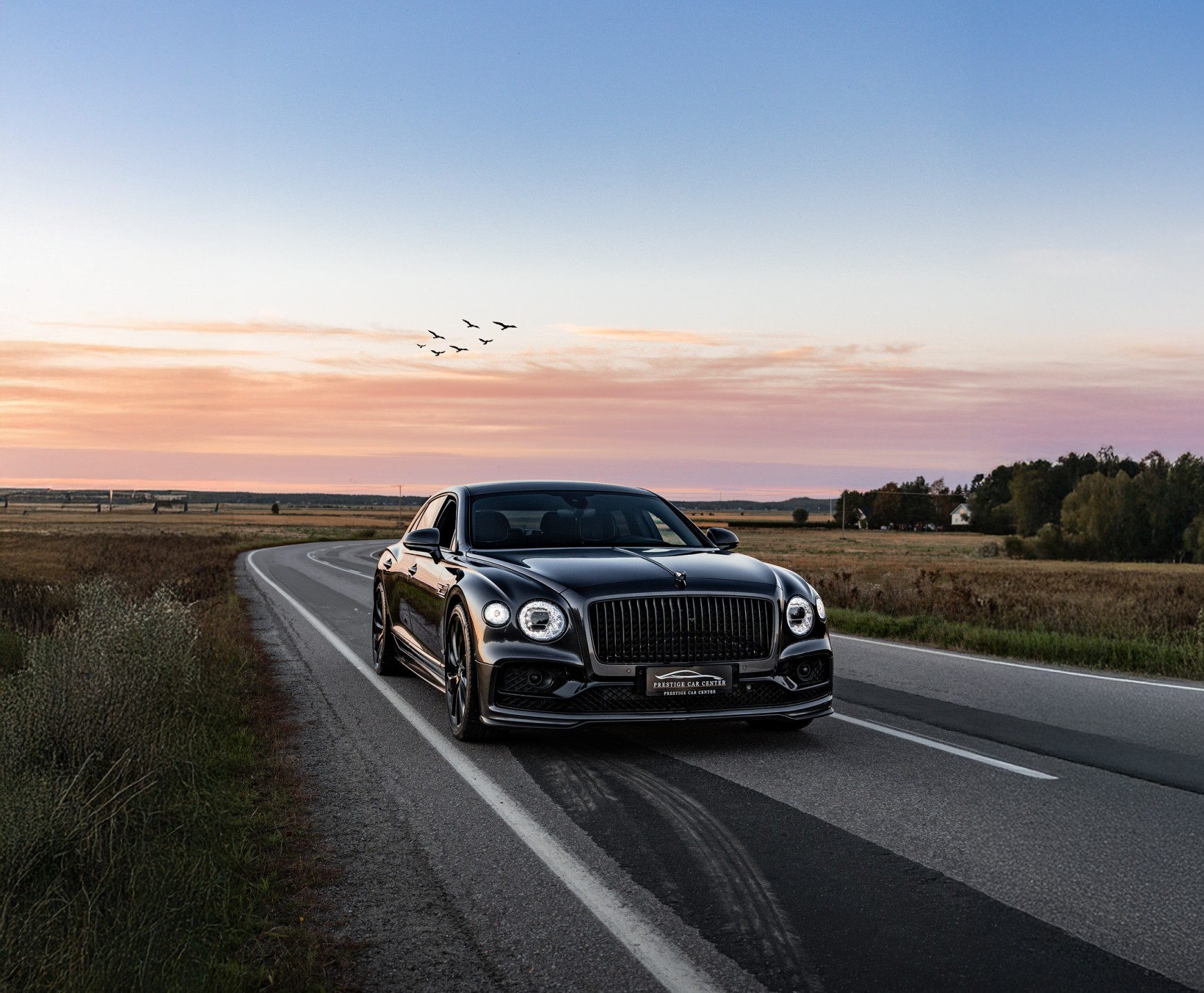 Bentley Flying Spur maantiellä auringonlaskussa