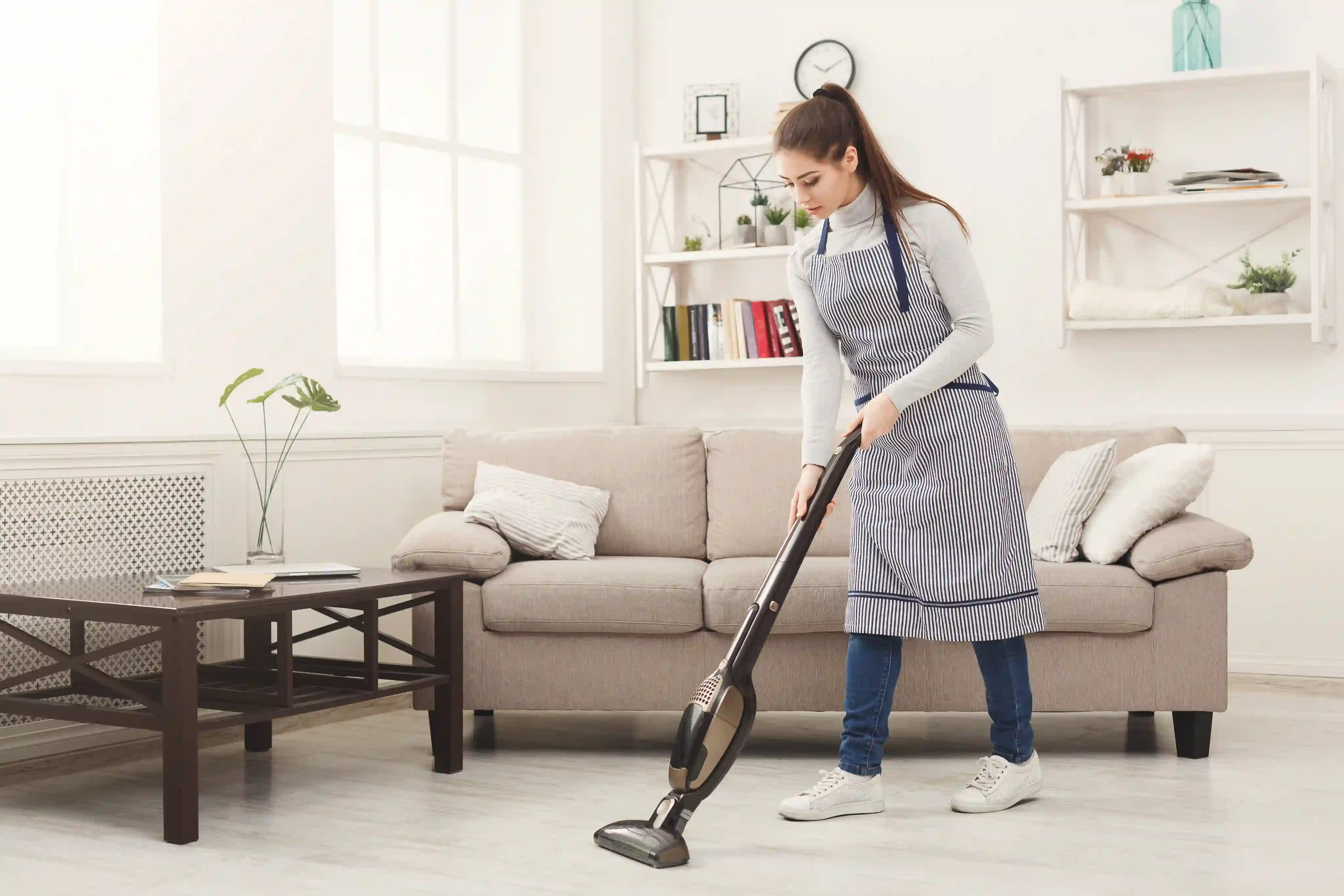 Cleaner vacuuming a bright living room