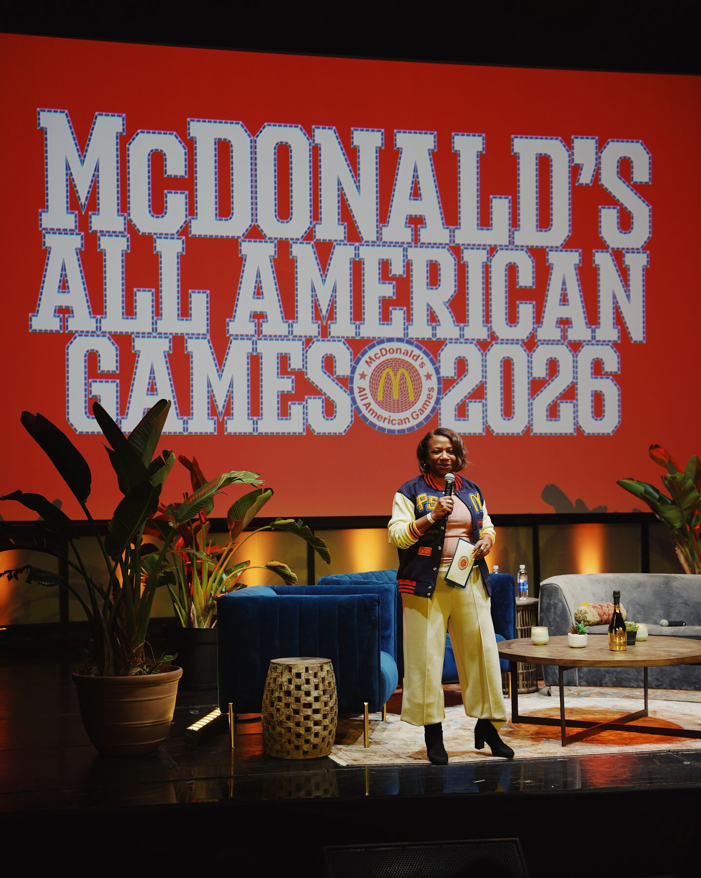 Host presenting in front of the McDonald's All American Games backdrop