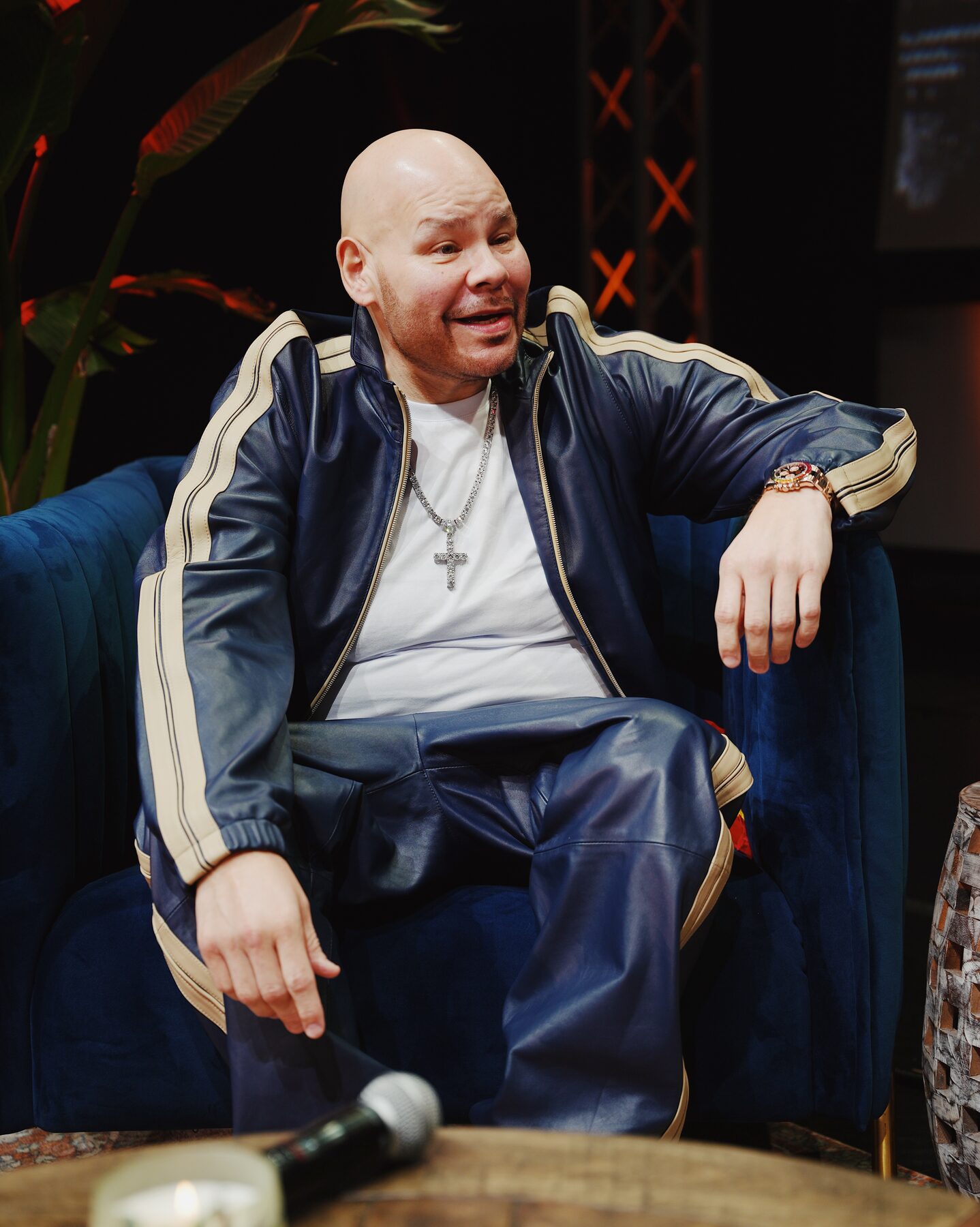 Host seated in the blue lounge chair on set