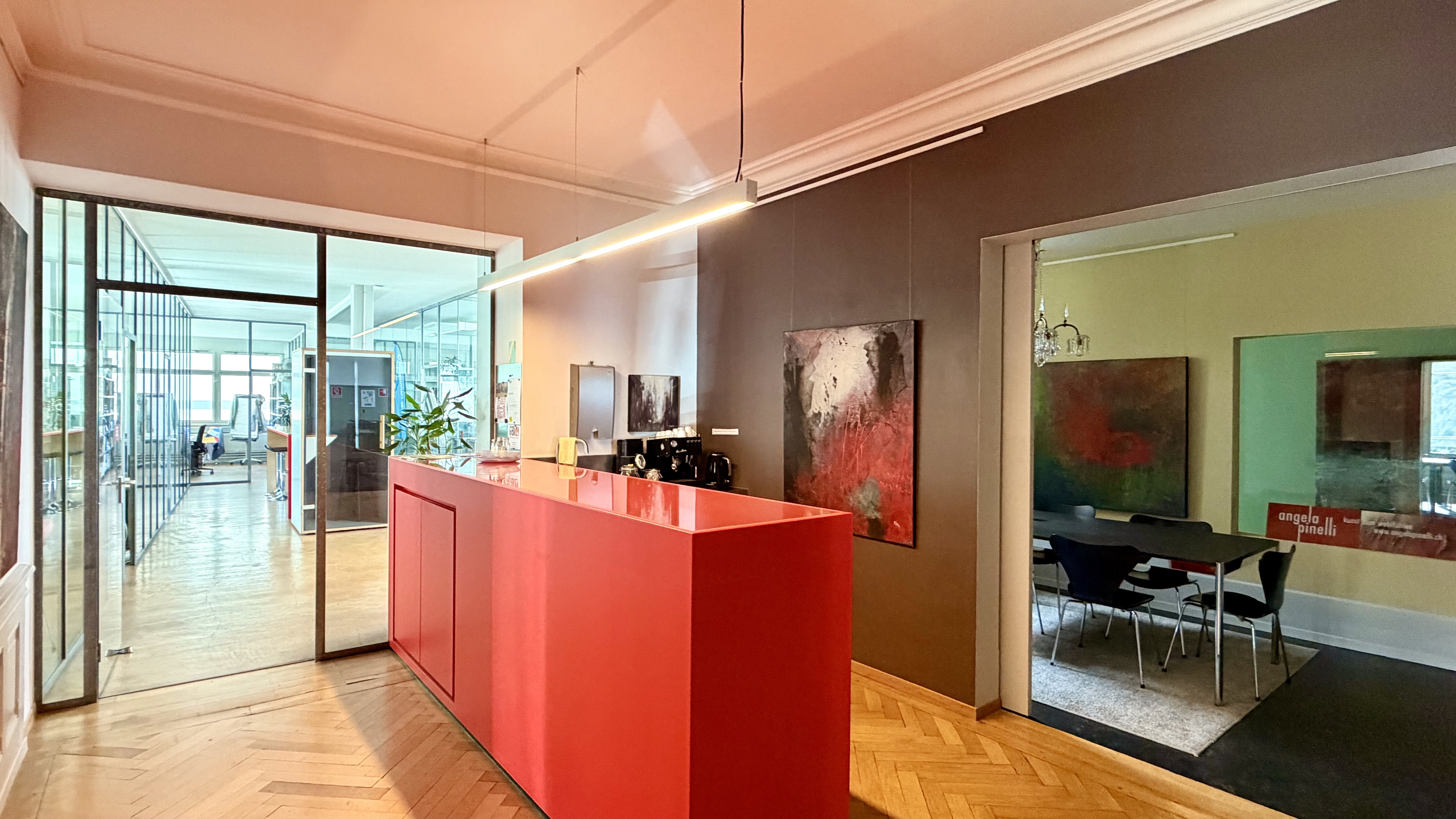 Innenarchitektur von allarch mit roter Küchenzeile, Parkettboden und offen gestaltetem Wohn- und Aufenthaltsbereich.