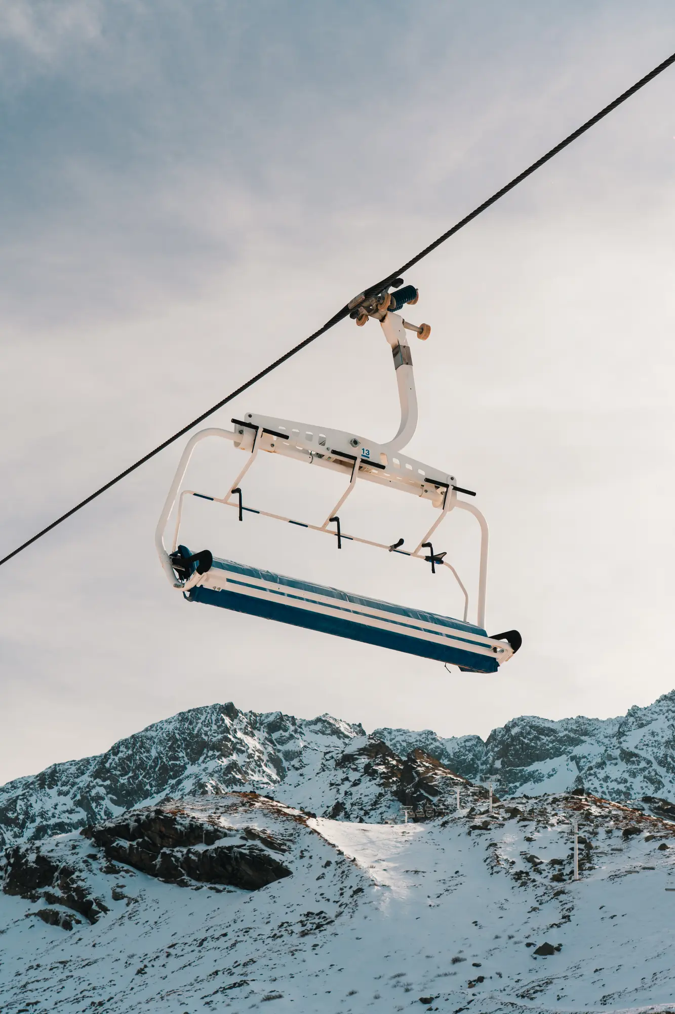 Une remontée mécanique suspendue au-dessus d'une montagne enneigée avec un ciel clair en arrière-plan.