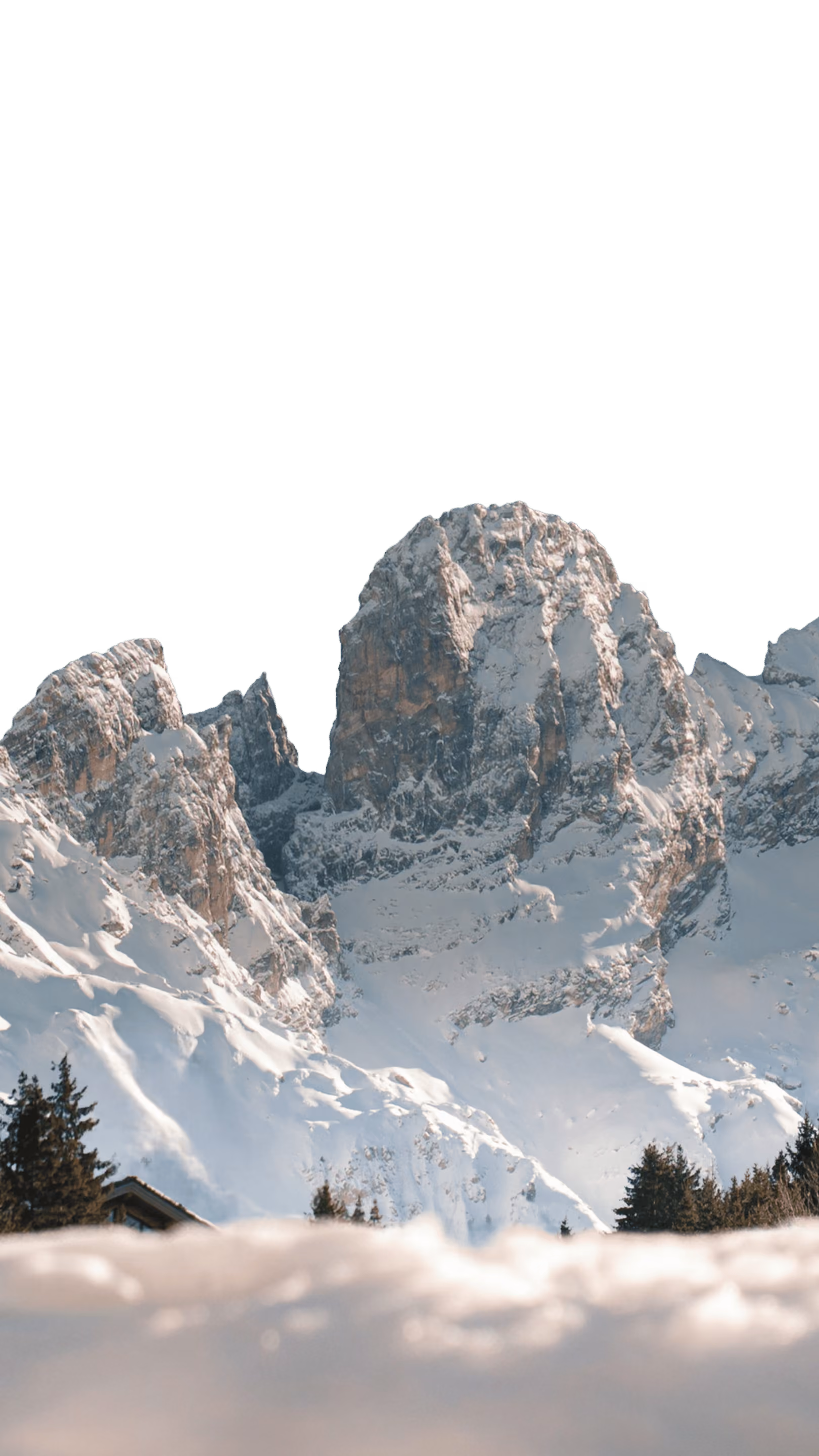 Montagne rocheuse imposante couverte de neige au-dessus de sapins verts et d’une maison partiellement visible, sous un ciel clair.