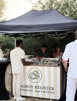 Person shucks an oyster over a tray filled with oysters and ice.