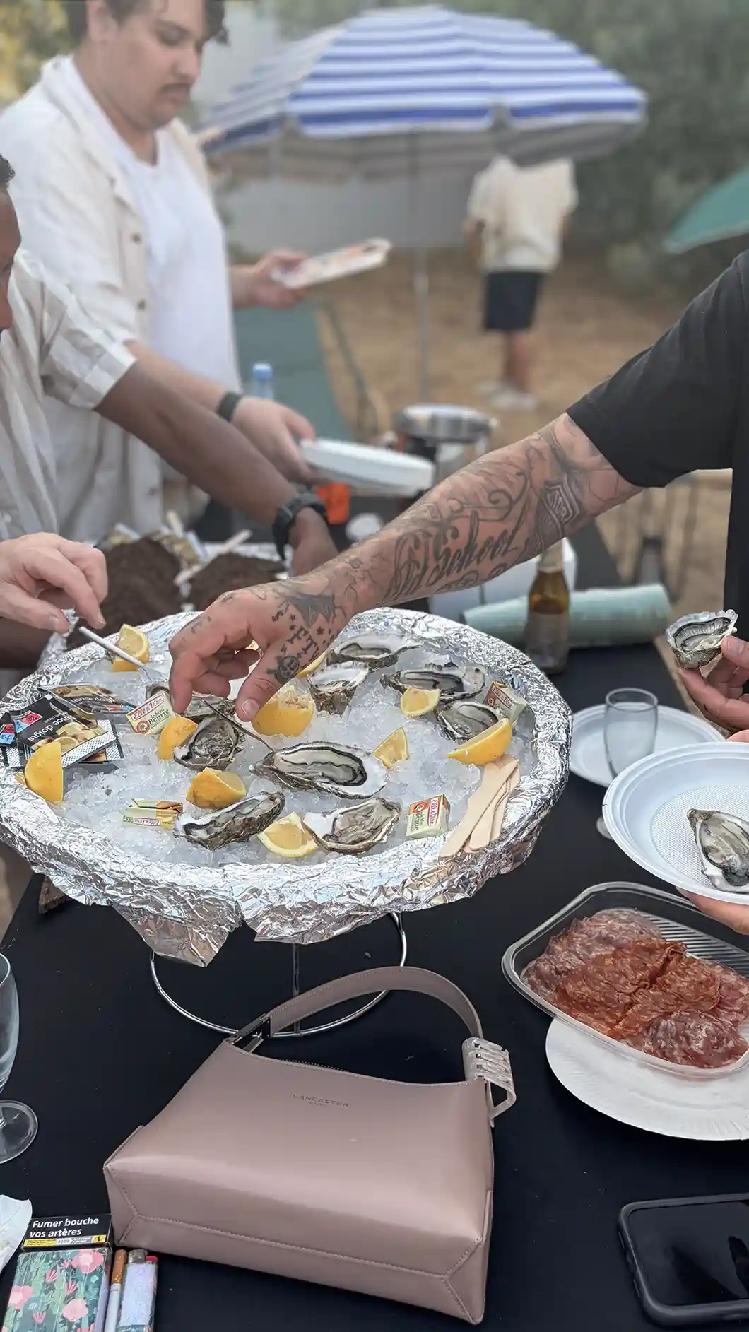 Person shucking oysters with a knife over a tray filled with oyster shells and ice.