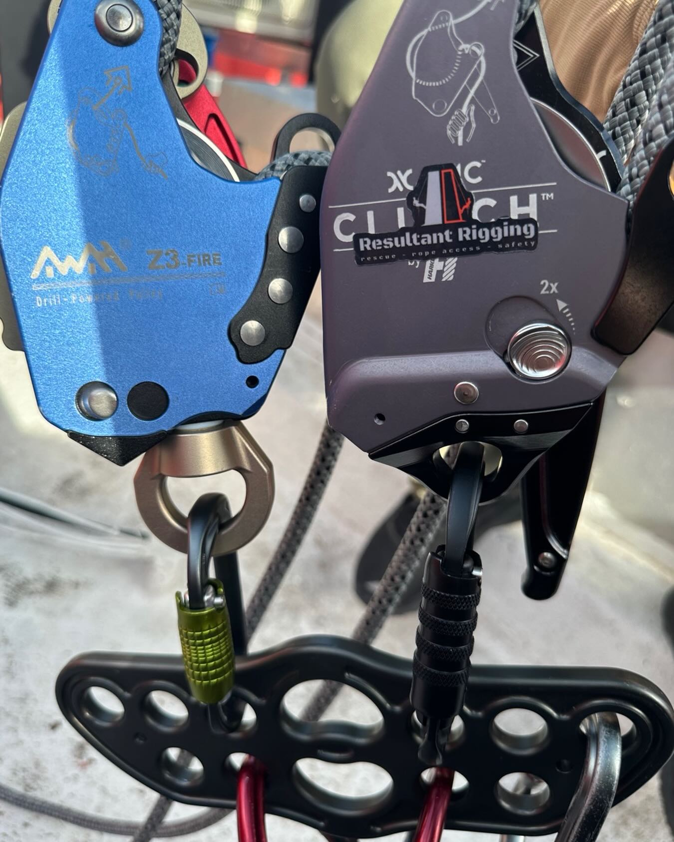 Close-up of two mechanical rope ascenders with carabiners and mounting plate for climbing or rescue.