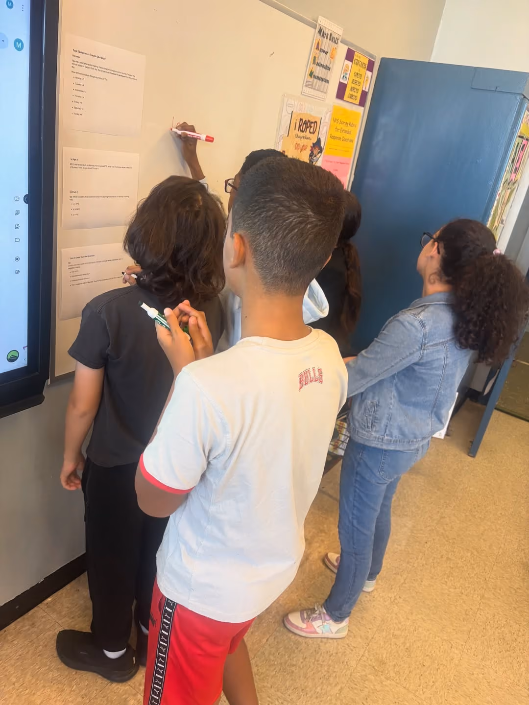 Students writing their solutions on a classroom whiteboard