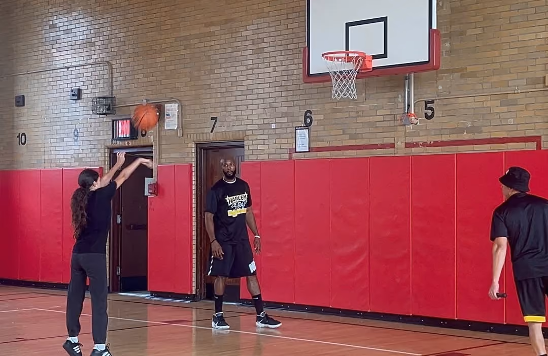 Harlem Magic Masters player and a student shooting baskets in the gym
