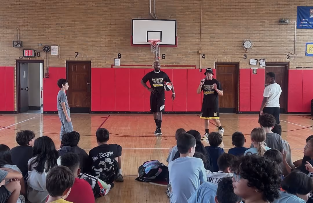 Students sitting on the gym floor watching the Harlem Magic Masters show